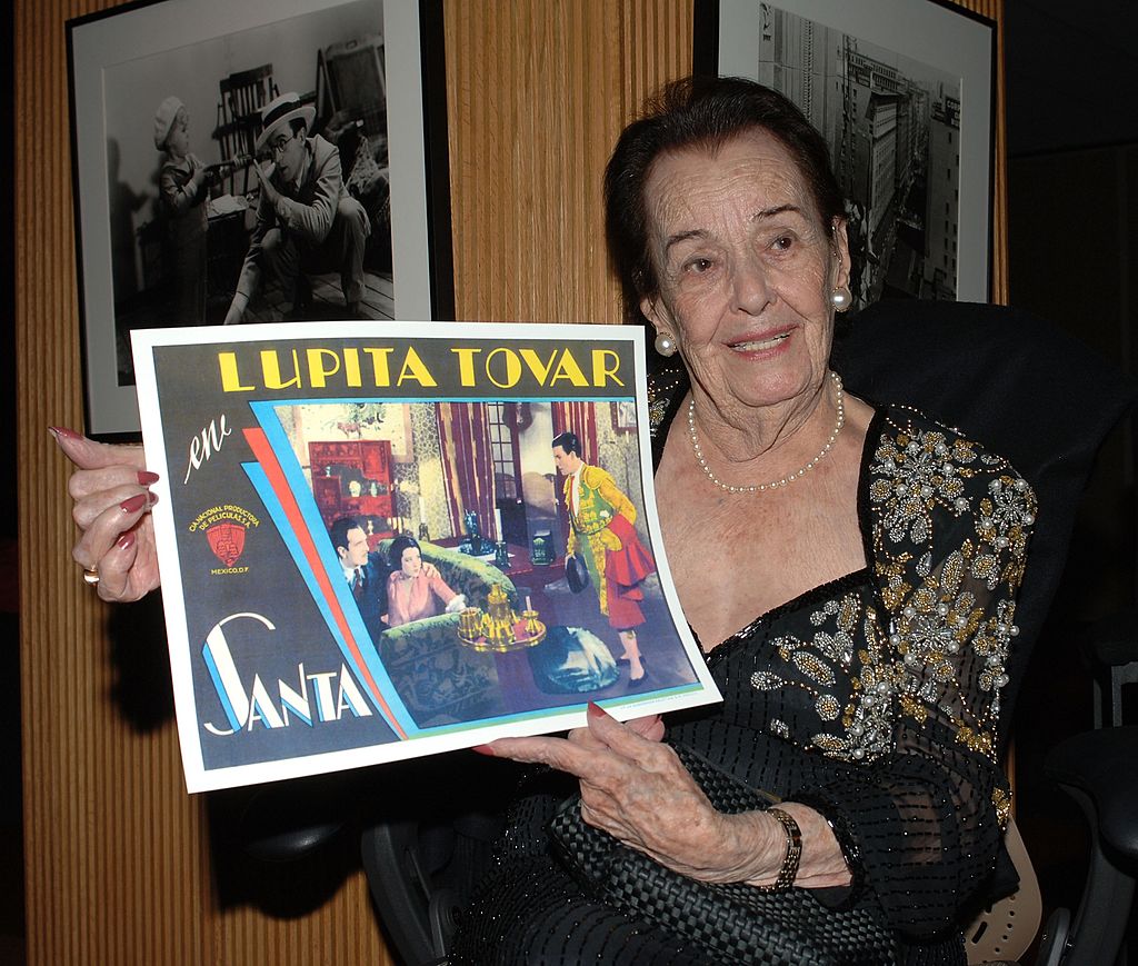 Lupita Tovar sostiene un póster de una de sus películas en su tributo en la Academia de Artes y Ciencias Cinematográficas el 7 de diciembre de 2006 en Beverly Hills, California. | Imagen: Getty Images