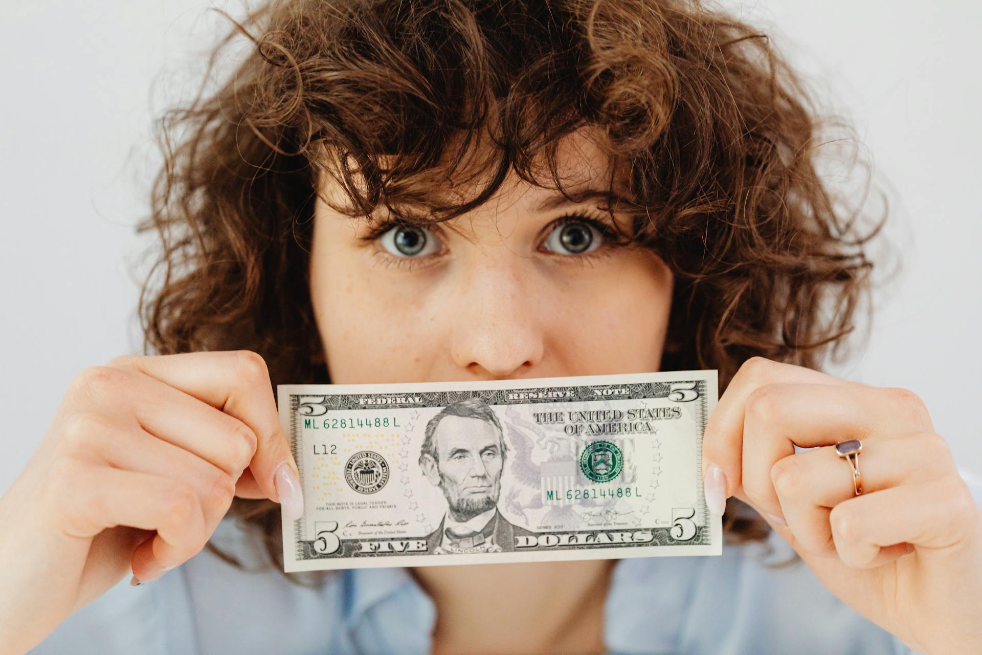 Una mujer con un billete de cinco dólares | Fuente: Pexels