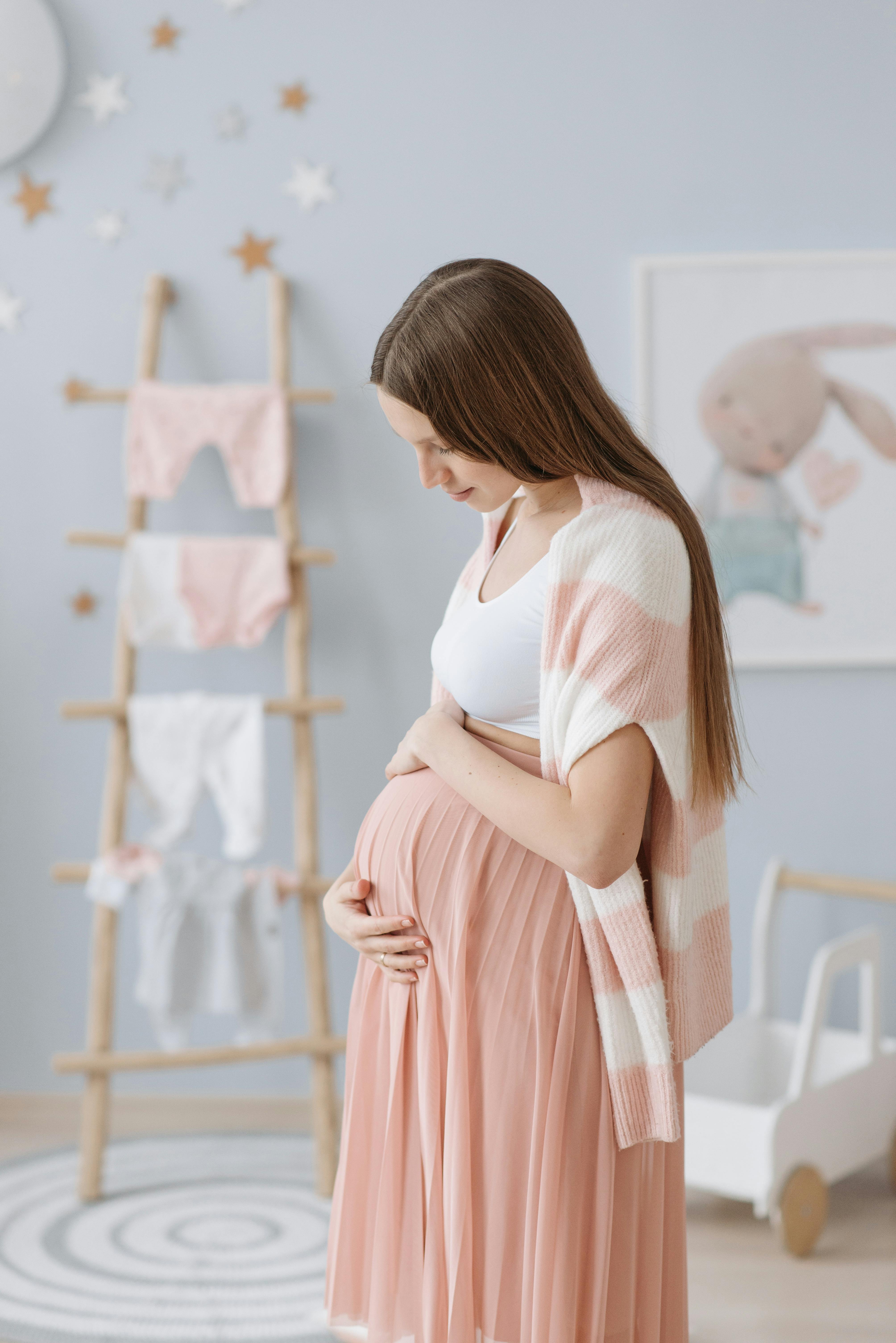 Una mujer embarazada sujetándose el vientre en la habitación de su futuro bebé | Foto: Pexels