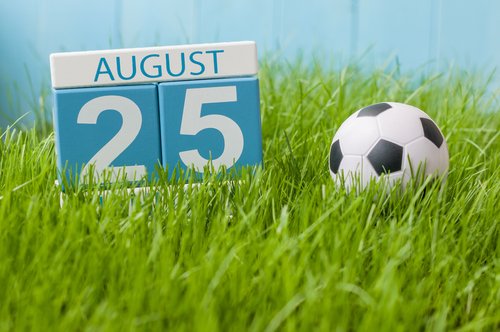 25 de agosto marcado en un calendario de madera junto a un balón de fútbol. | Fuente: Shutterstock