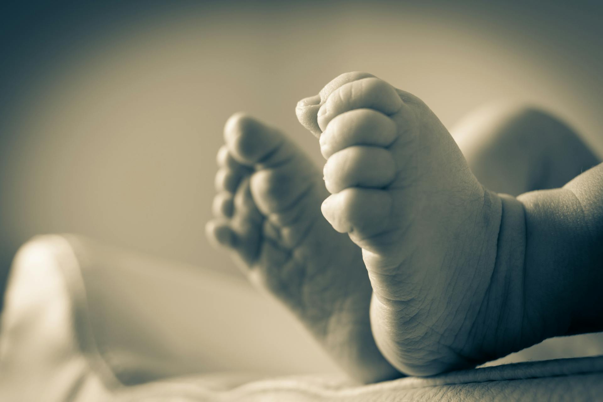 Foto en escala de grises de los pies de un recién nacido | Fuente: Pexels