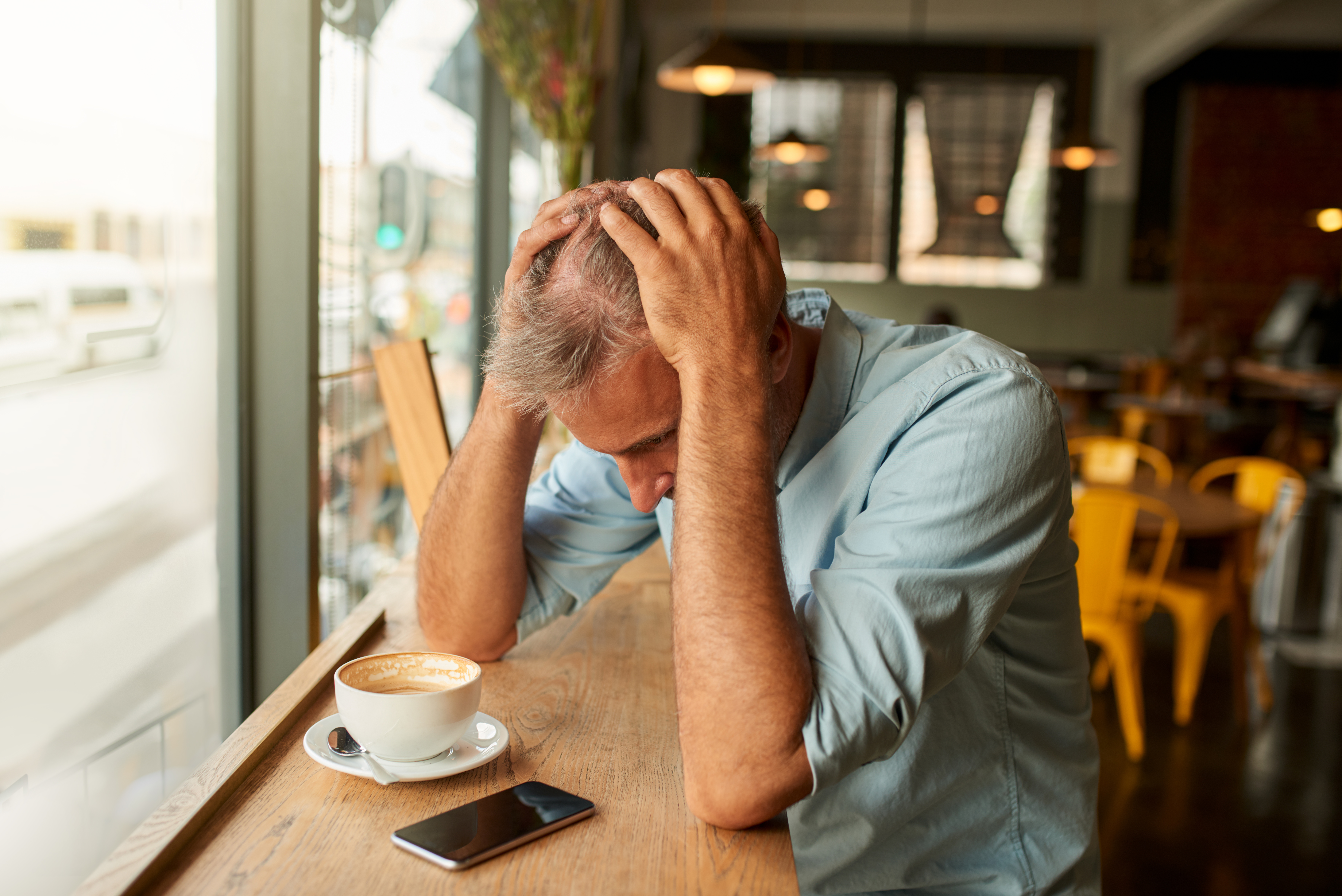 Un hombre estresado mirando su móvil en una cafetería | Foto: Getty Images