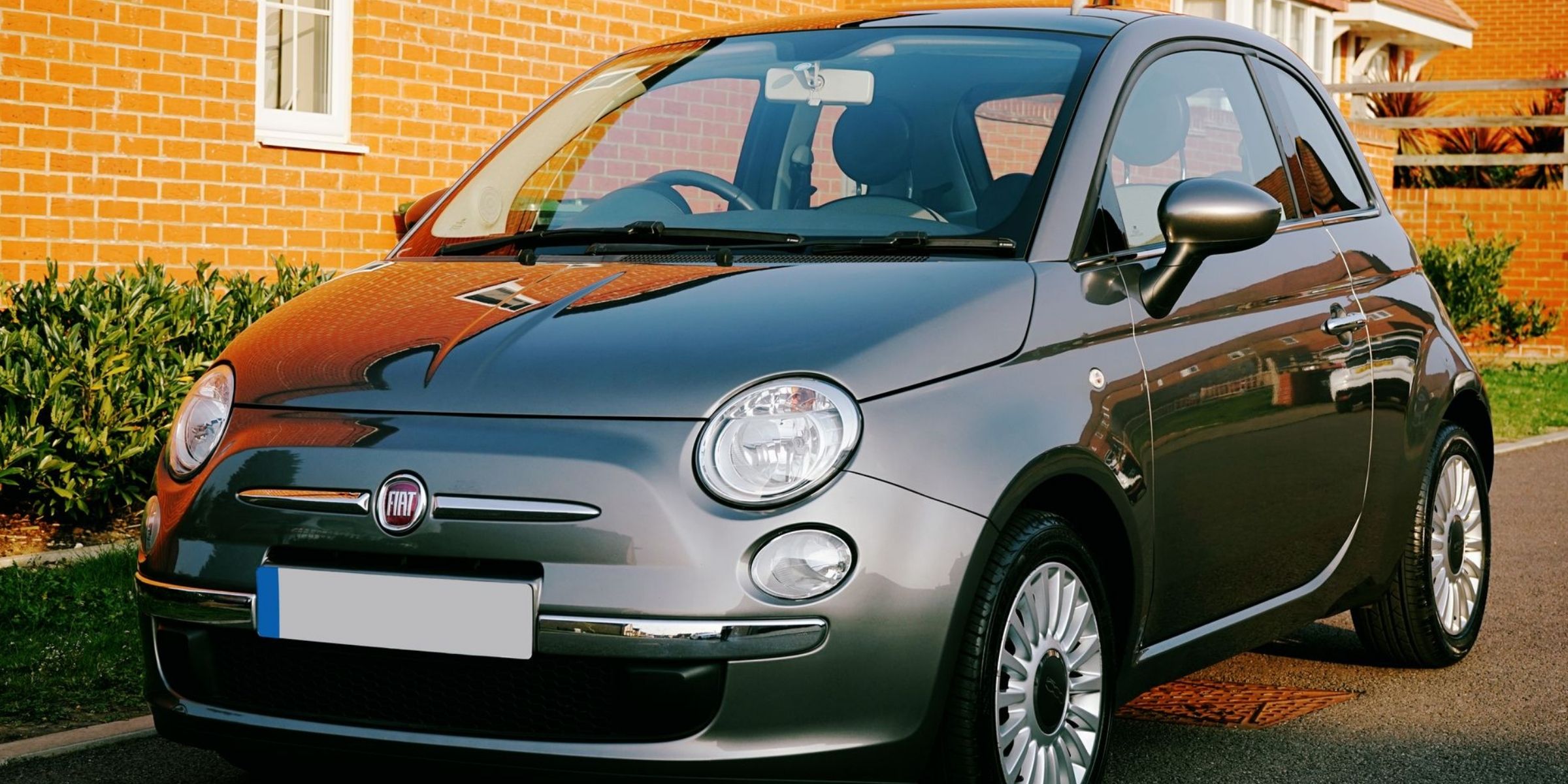 Una Fiat compatta grigia parcheggiata davanti a una casa in mattoni | Fonte: Pexels