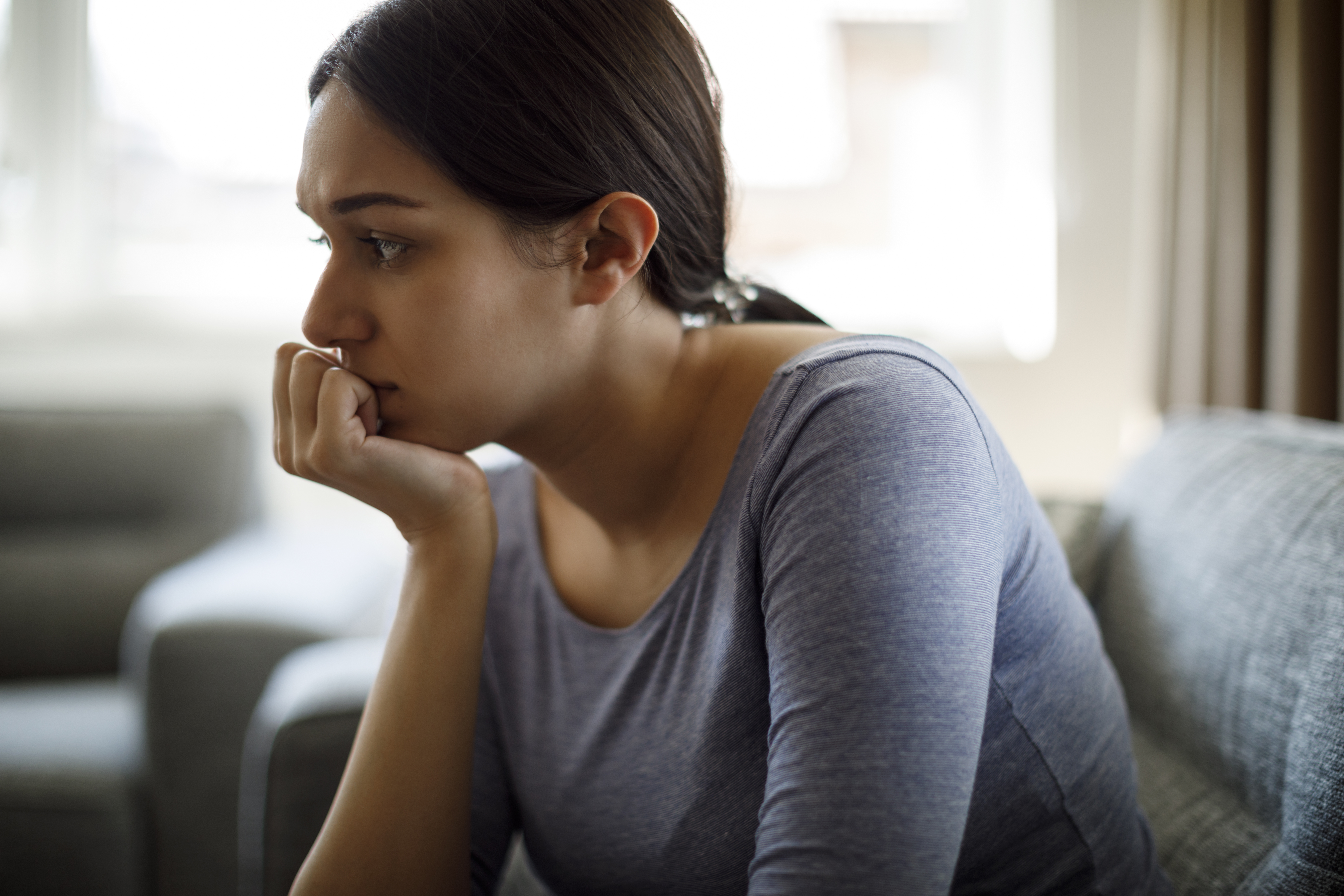 Mujer disgustada sentada en el sofá sola en casa | Fuente: Getty Images