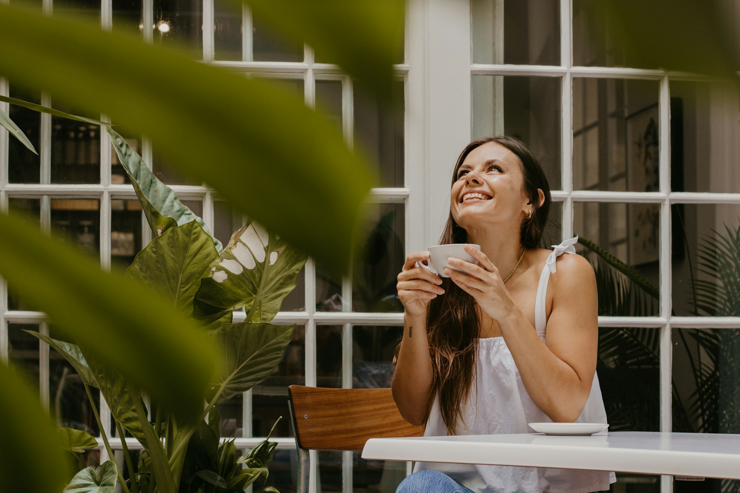 Una joven sonríe mientras sostiene una taza de café | Fuente: Unsplash