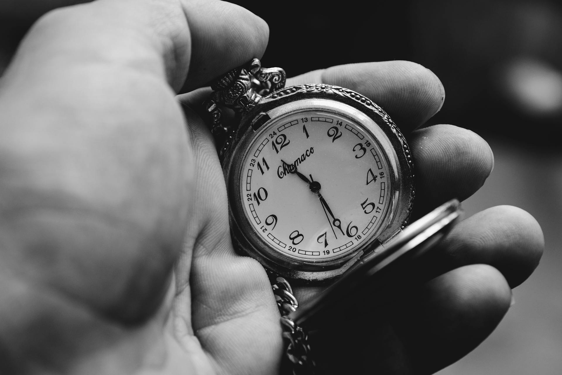 Toma en escala de grises de una persona sujetando un reloj de bolsillo antiguo | Fuente: Pexels