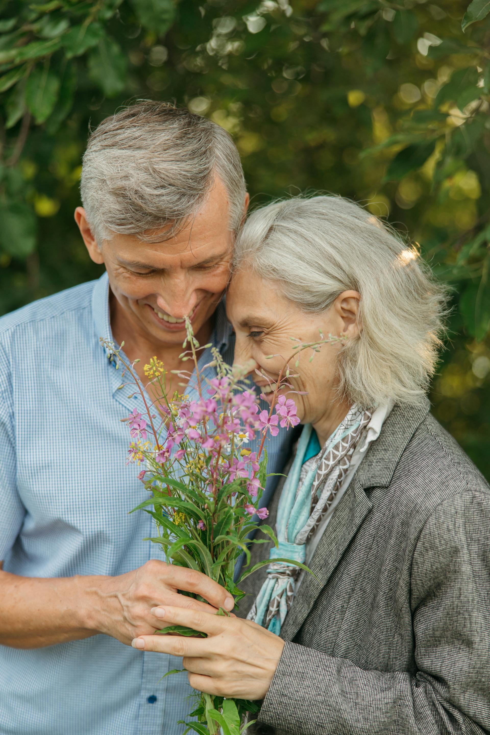 Primer plano de una pareja de ancianos sosteniendo flores | Foto: Pexels