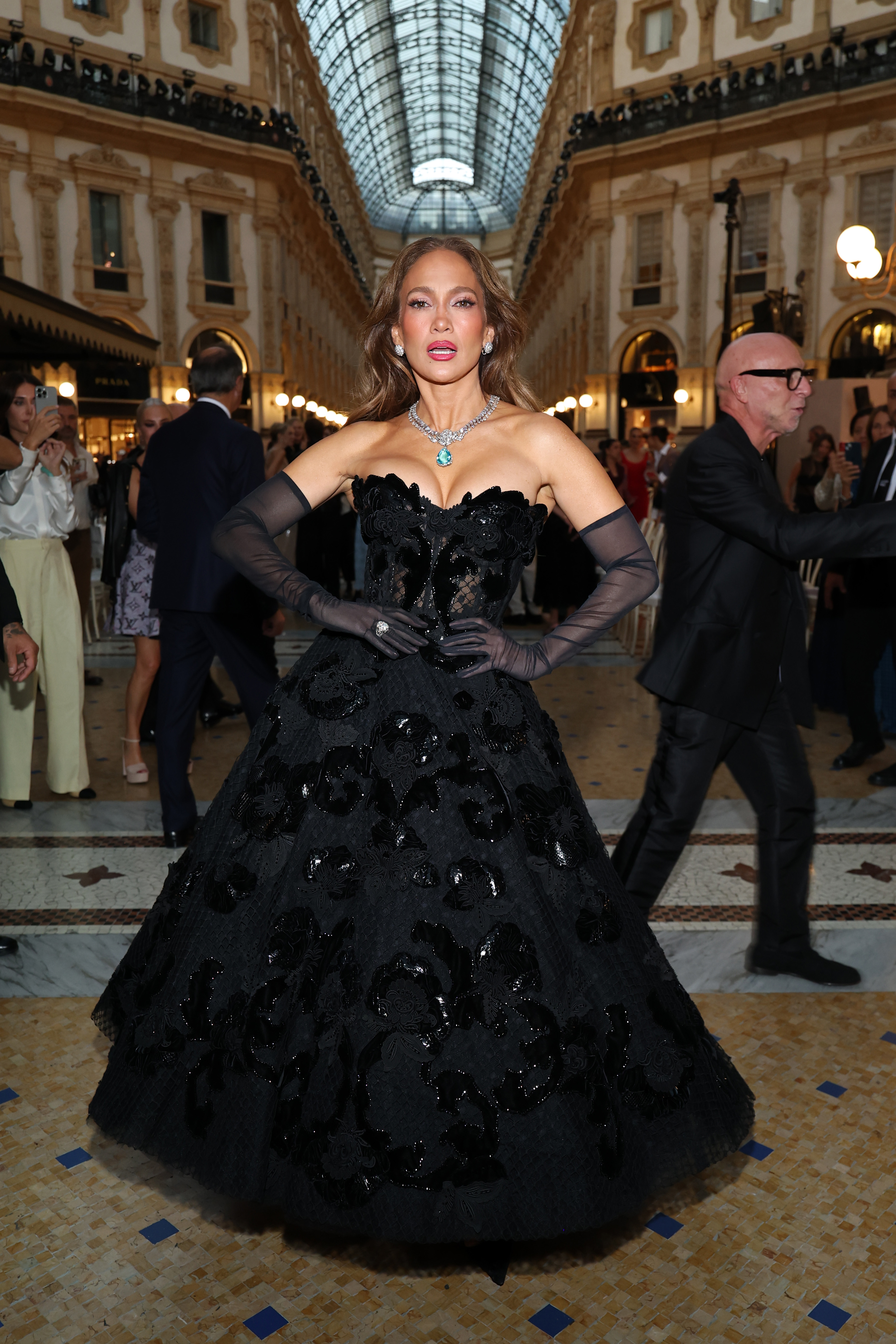 López posa con las manos en la cintura, luciendo la silueta y los detalles florales de su vestido de gala negro. | Fuente: Getty Images