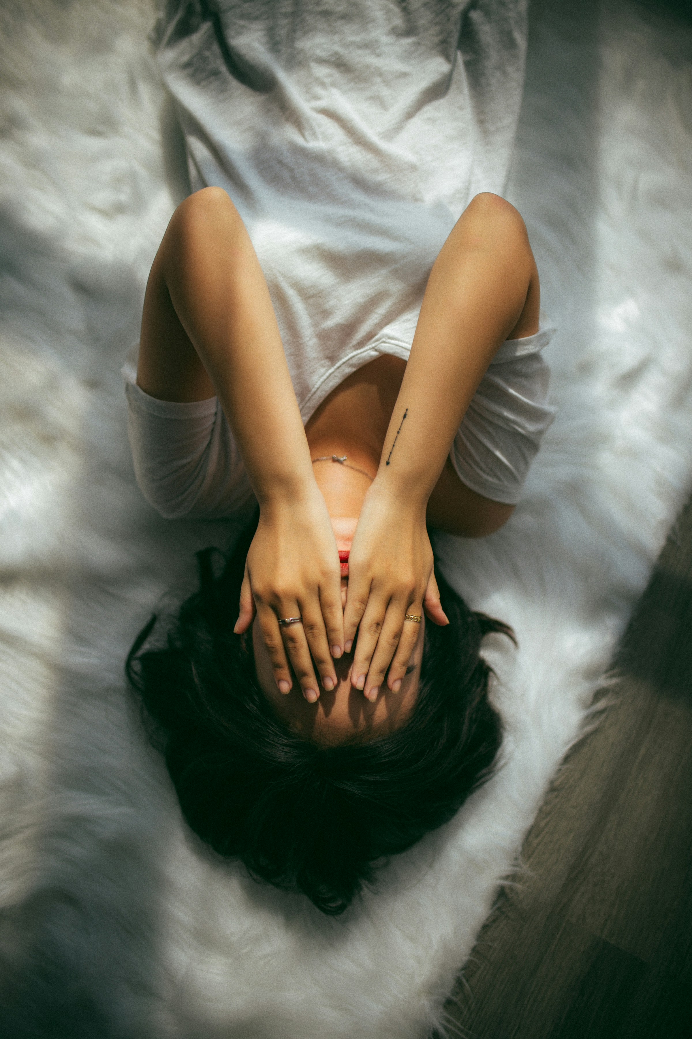 Una mujer tumbada en la cama ocultando su rostro | Foto: Unsplash