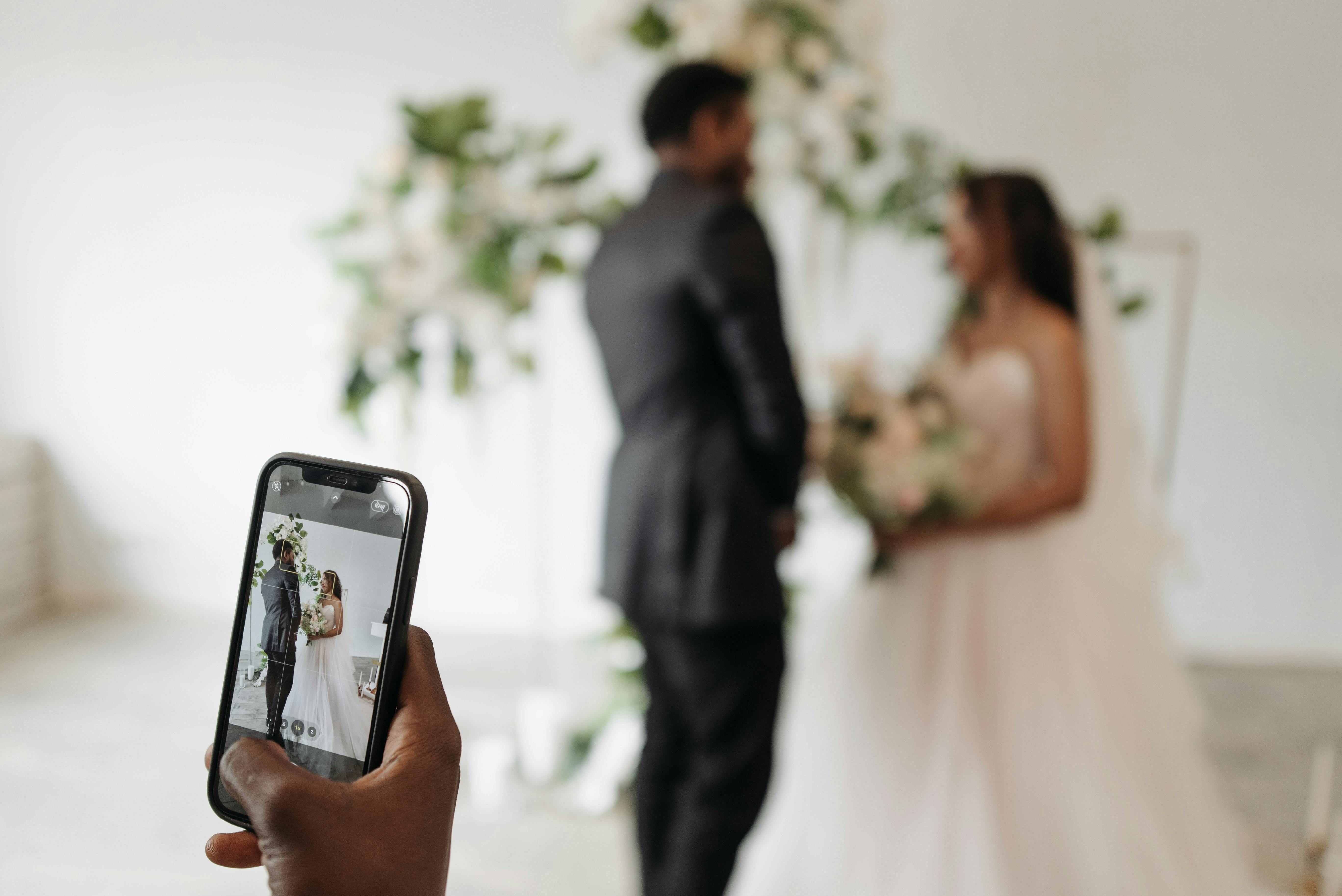 Alguien grabando con su teléfono a unos recién casados | Foto: Pexels