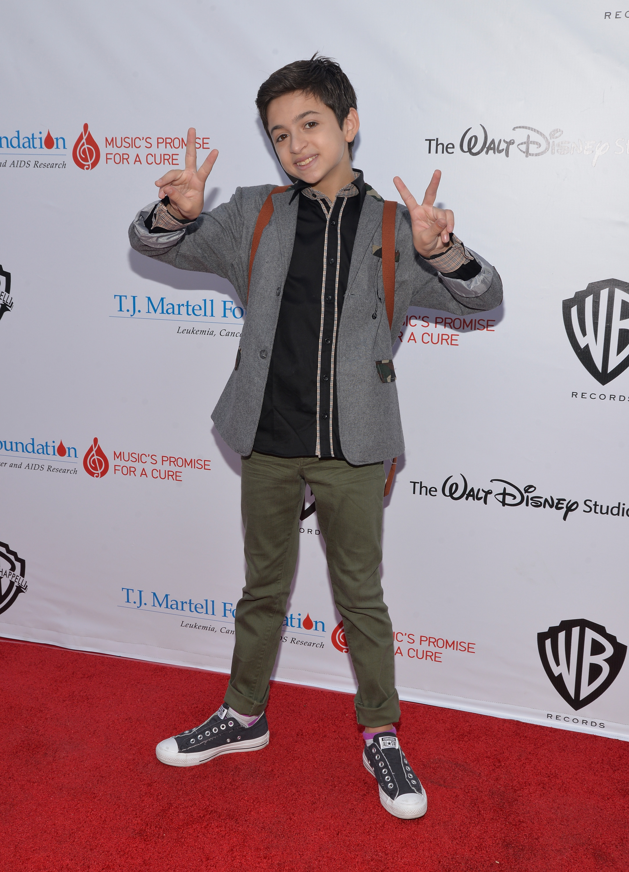 Hace el gesto de la paz en la alfombra roja del 6º evento anual "Family Day LA" de la Fundación T.J. Martell, celebrado en Studio City, California, vestida con una chaqueta gris, una camiseta negra, unos pantalones verde oliva y unas zapatillas altas negras. | Fuente: Getty Images