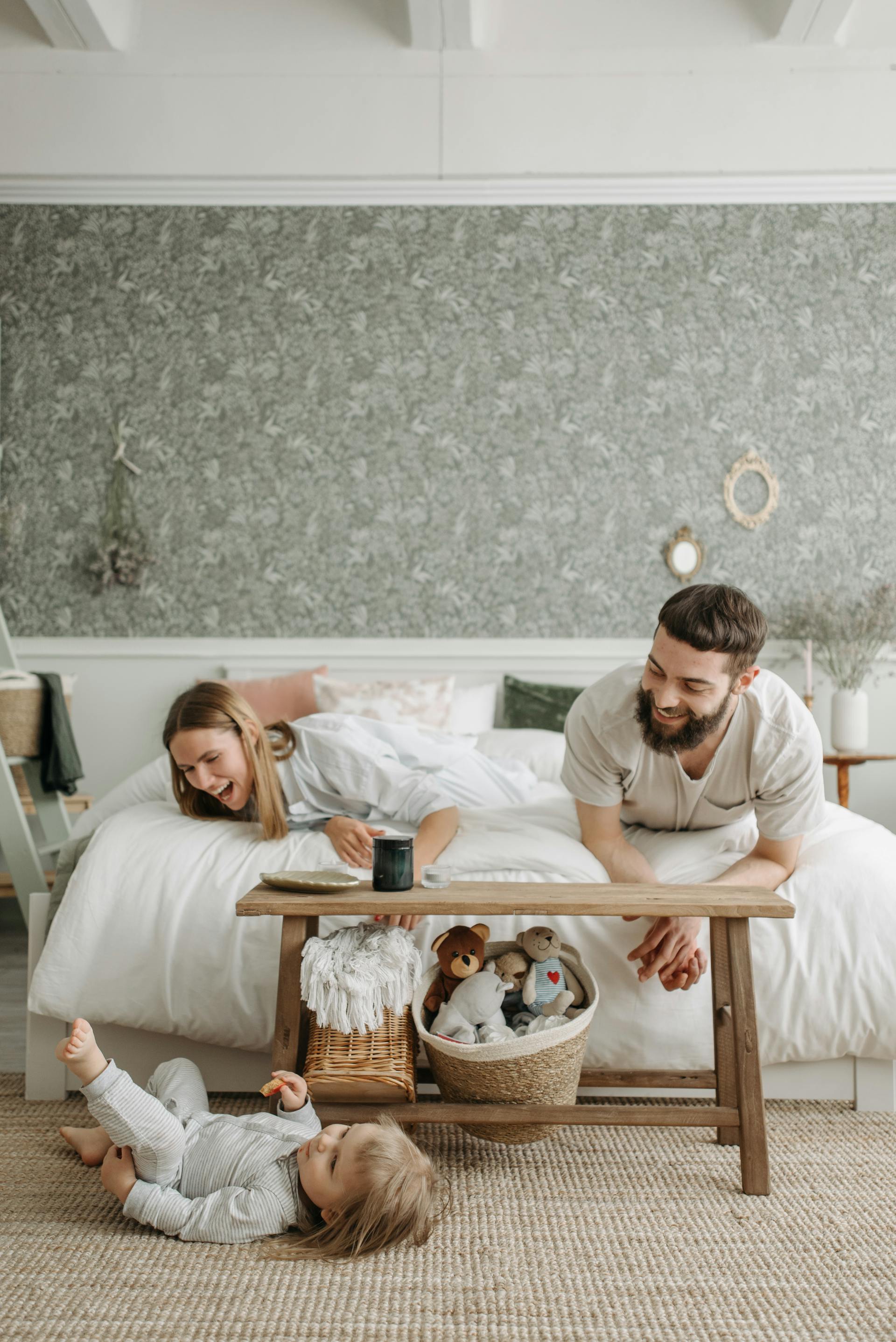 Pareja feliz jugando con su hija pequeña en el dormitorio | Foto: Pexels