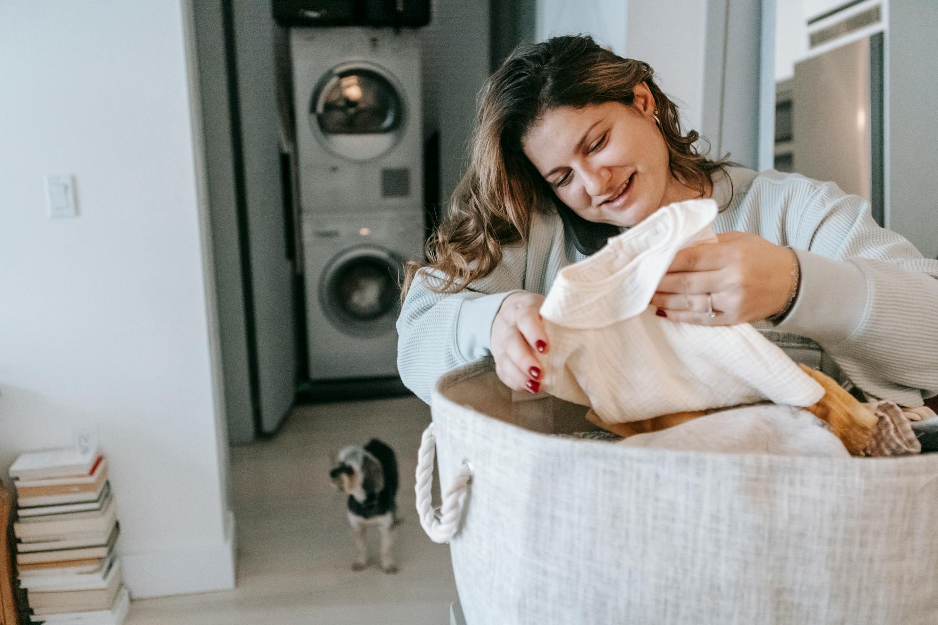 Una mujer sonríe esperanzada mientras dobla la ropa | Fuente: Pexels