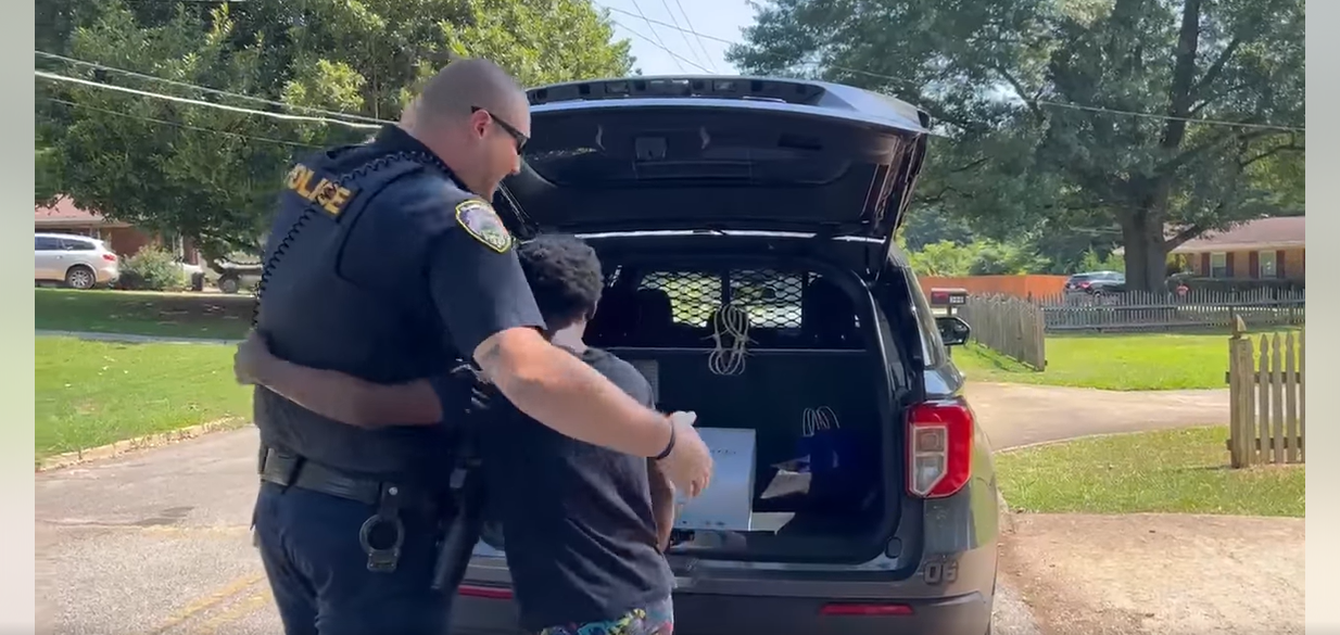 El oficial Colleran recibe un abrazo de un niño después de llevarlo al maletero de su coche para mostrarle algo el 24 de julio de 2023 | Foto: Facebook/City of Hapeville Police