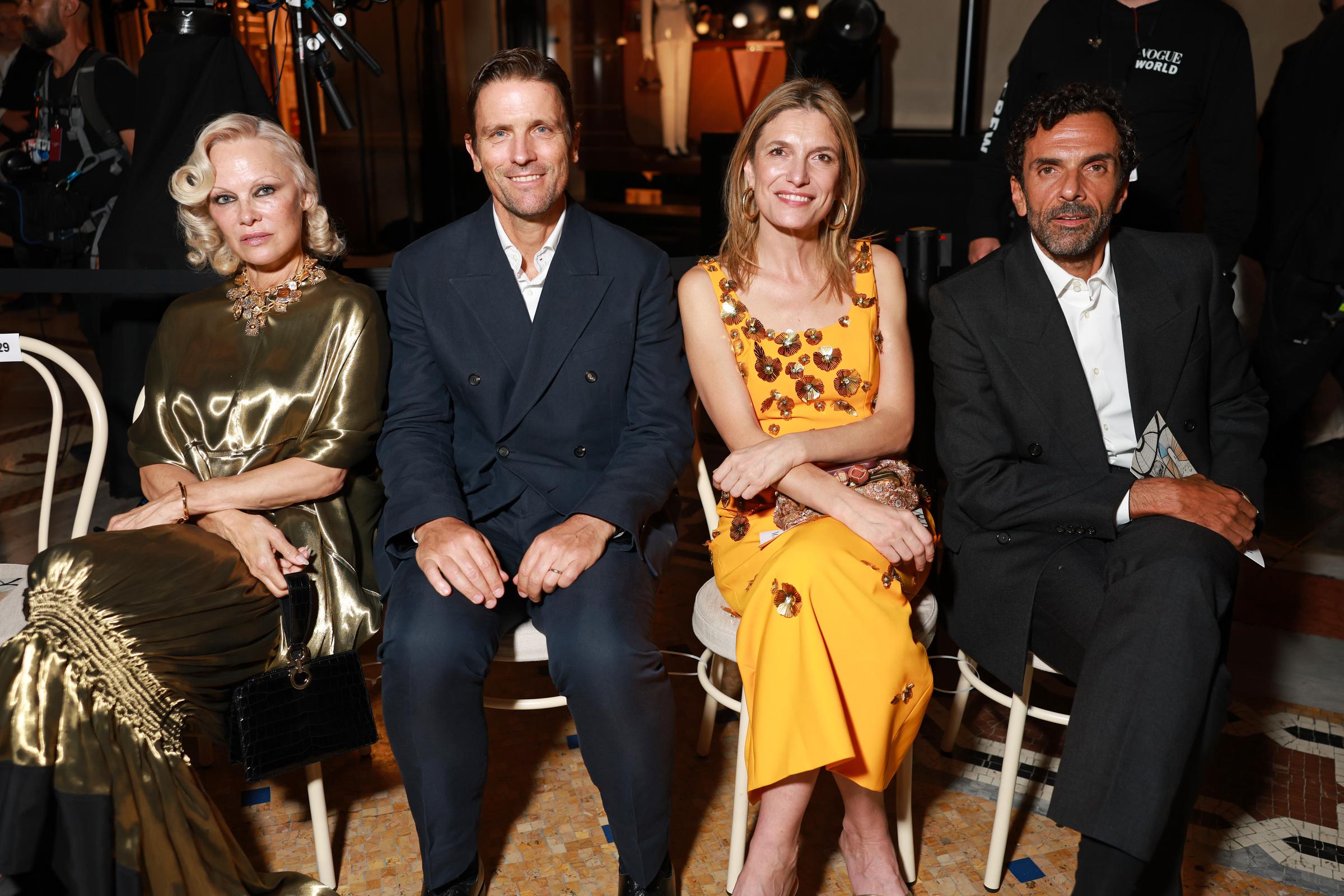 Pamela Anderson está sentada junto a otros asistentes al evento «Vogue World: Milán 2026» en la Galleria Vittorio Emanuele II el 22 de septiembre de 2026. Su vestido dorado metalizado, su llamativo collar y su maquillaje de ojos ahumados llamaron la atención en el recinto de Milán. | Fuente: Getty Images