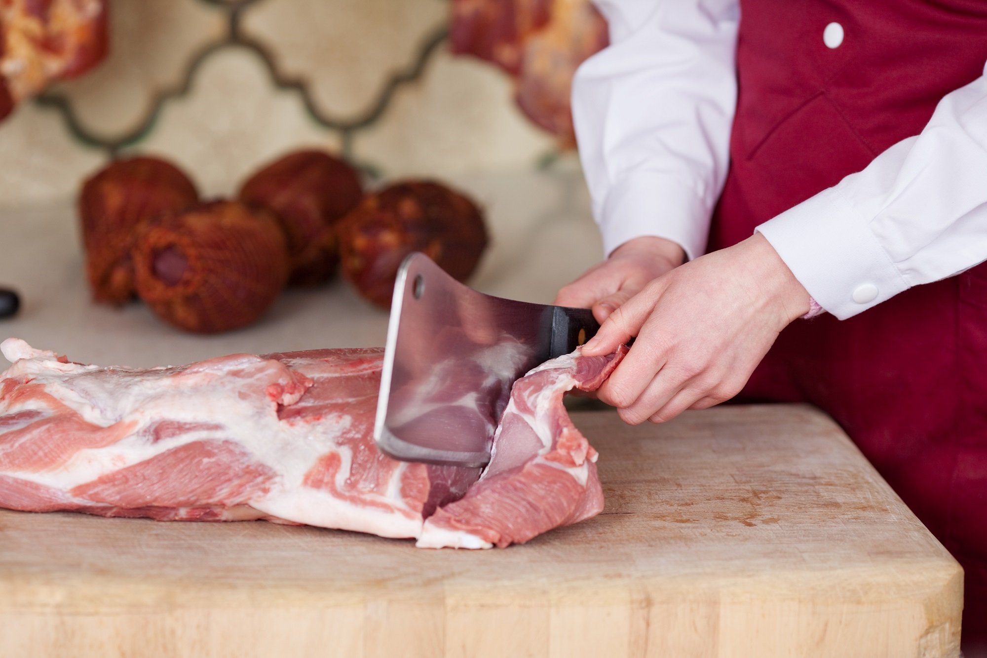 Hombre cortando carne fresca con cuchillo de carnicero. | Foto: Shutterstock