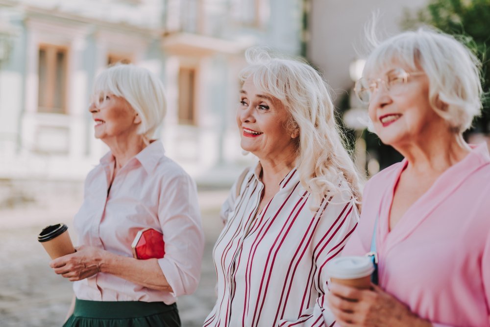 Tres abuelas con estilo caminando en la calle y sonriendo. Fuente: Shutterstock