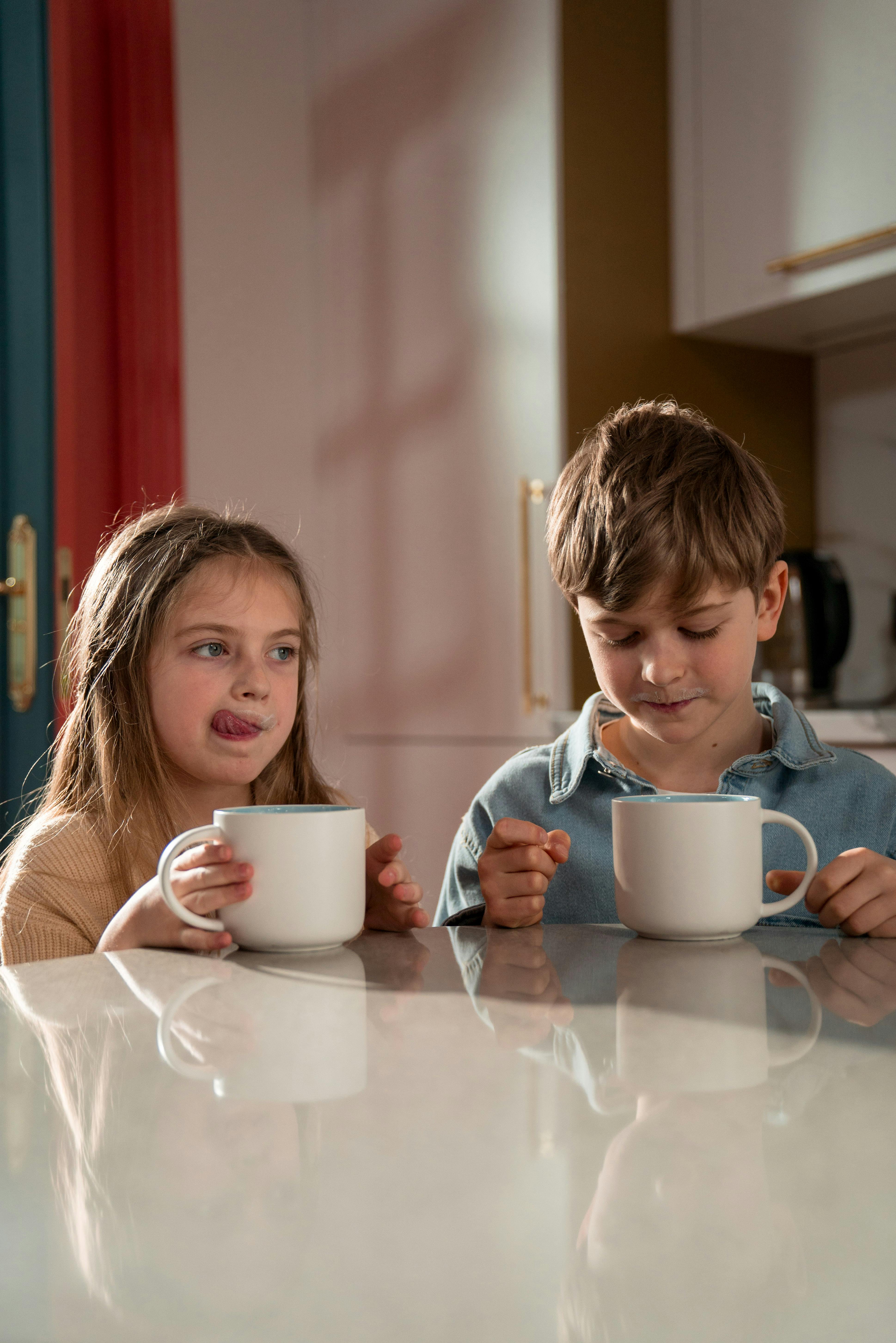 Dos niños sentados a la mesa y disfrutando de sus bebidas | Fuente: Pexels