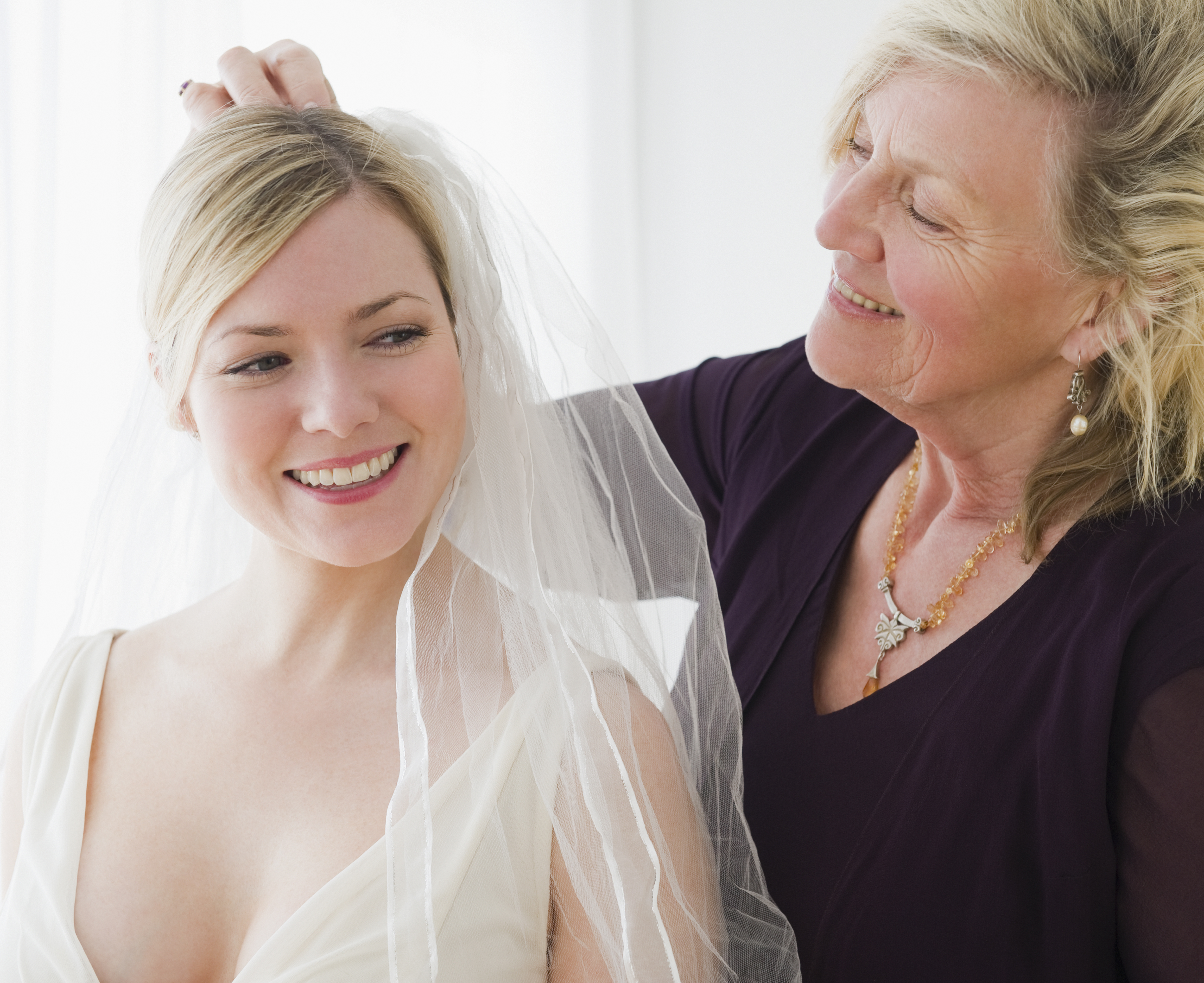 Una mujer mayor ayuda a una mujer más joven a probarse un vestido de novia | Foto: Getty Images