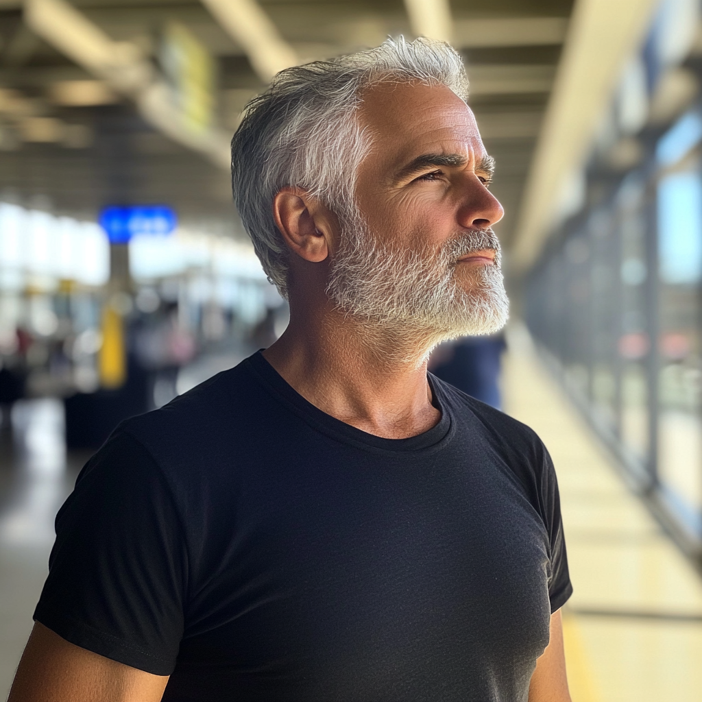 Un hombre de pie en un aeropuerto | Fuente: Midjourney