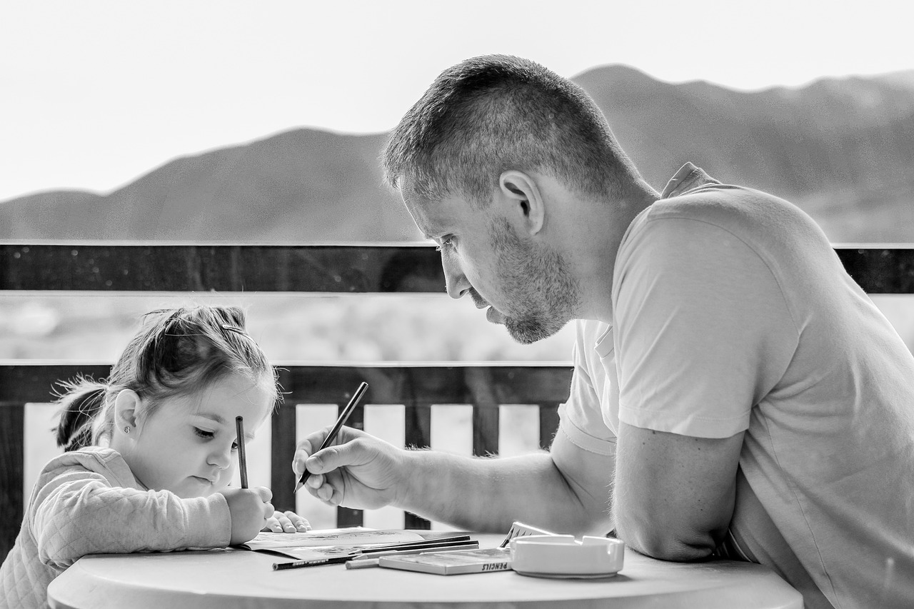Hombre ayudando a una niña con sus deberes escolares | Fuente: Pixabay