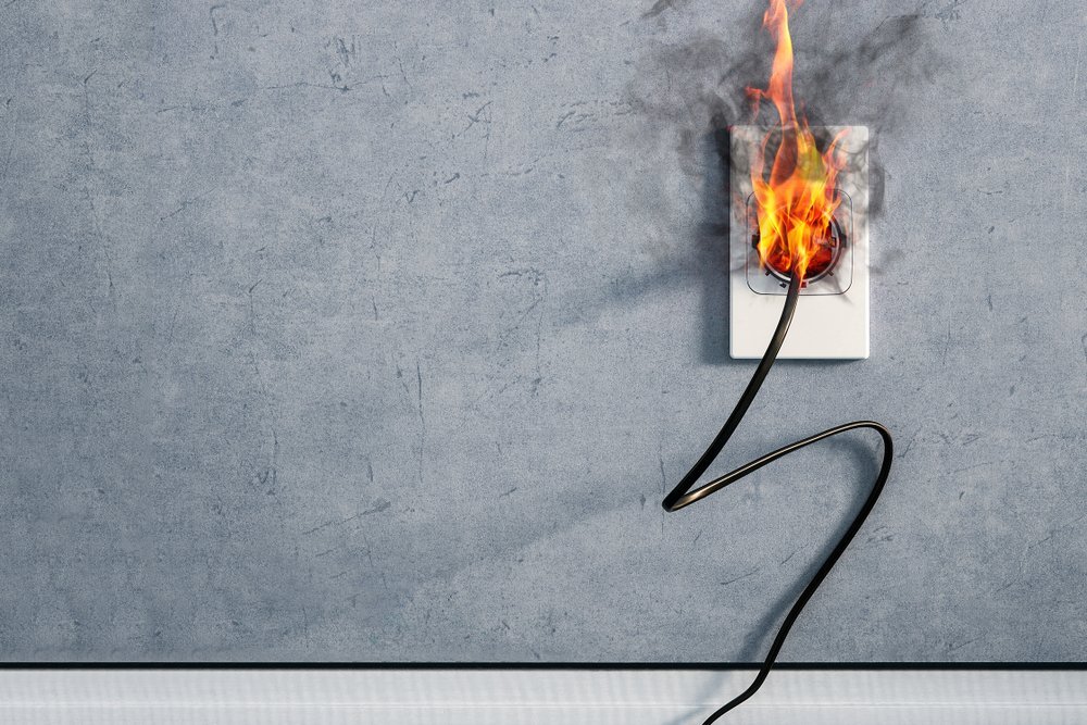 Incendio y humo en el enchufe del cable eléctrico por cortocircuito interior. Fuente: Shutterstock