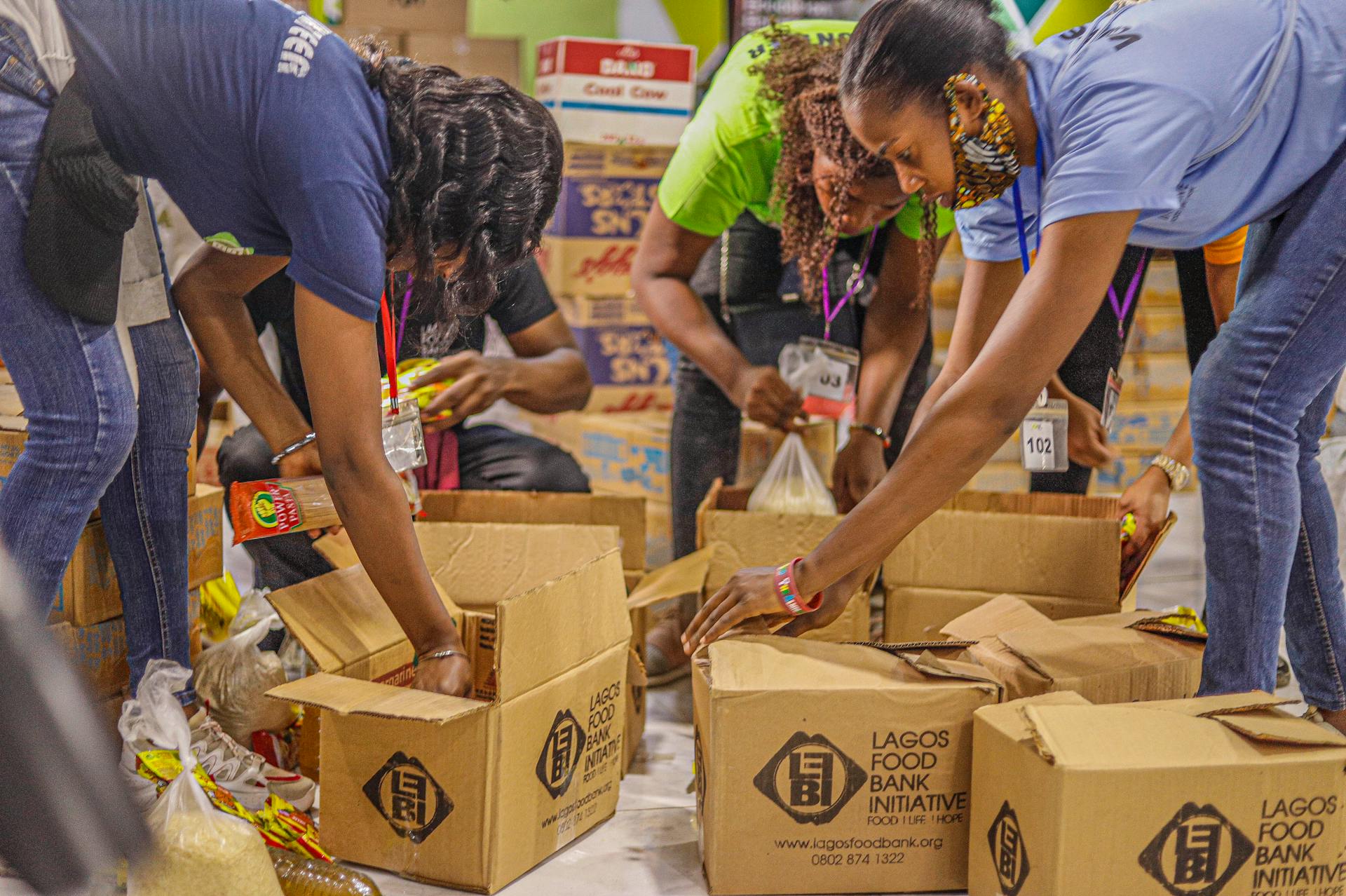 Voluntarios de un banco de alimentos empaquetando artículos dentro de cajas de cartón | Fuente: Pexels