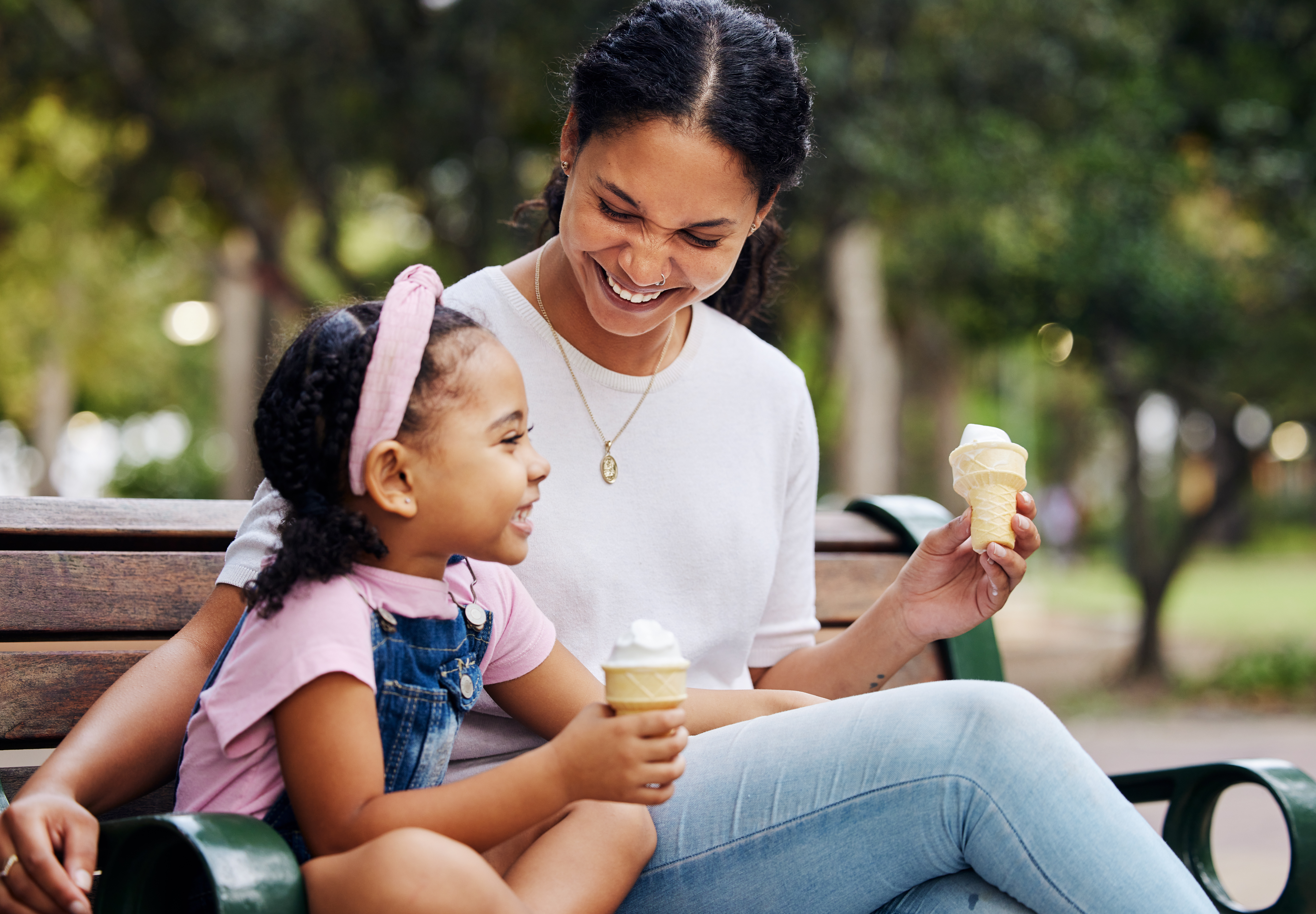 Una madre y su hija tomando un helado en un banco del parque | Foto: Getty Images