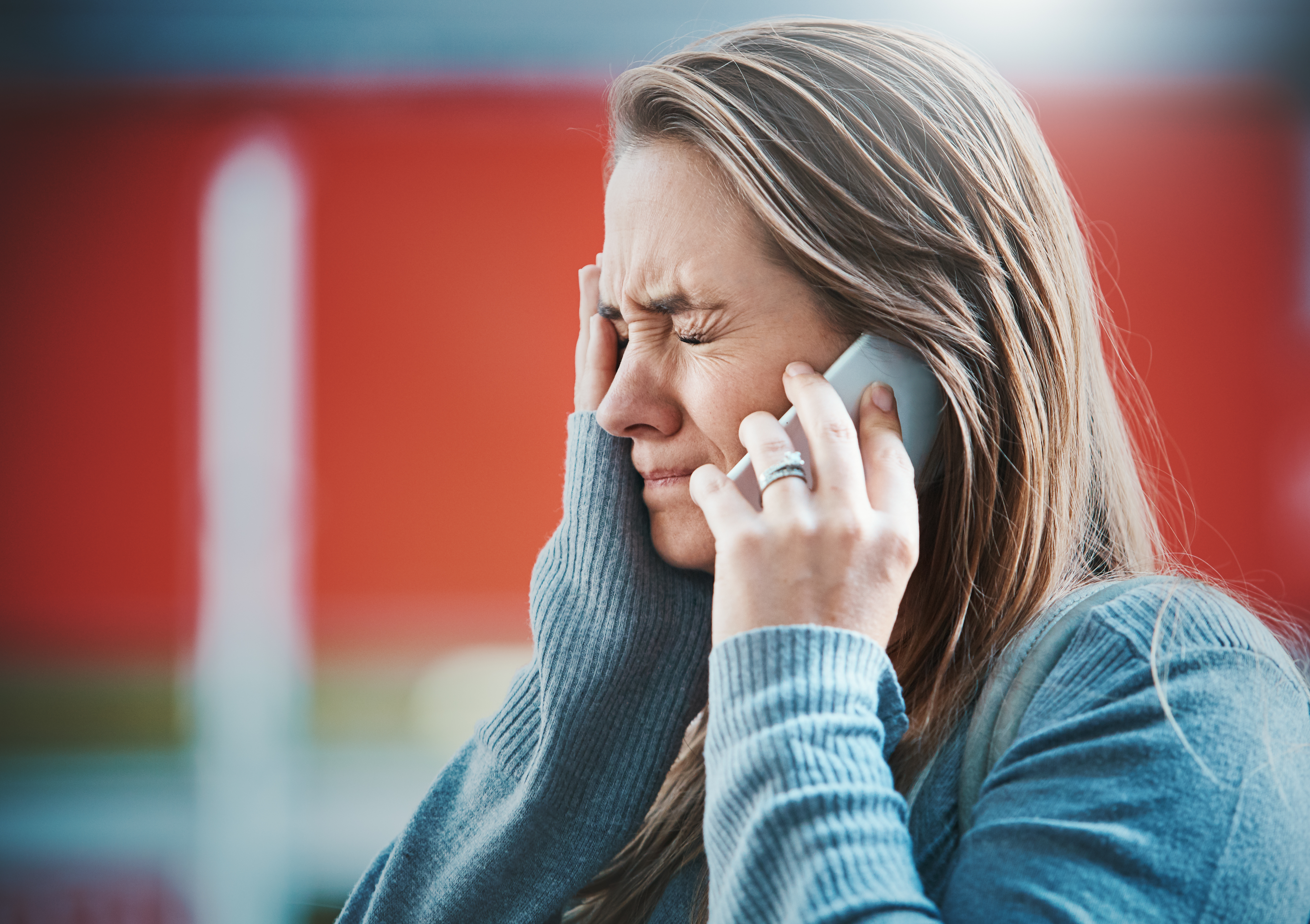 Mujer joven conteniendo las lágrimas por teléfono | Fuente: Getty Images
