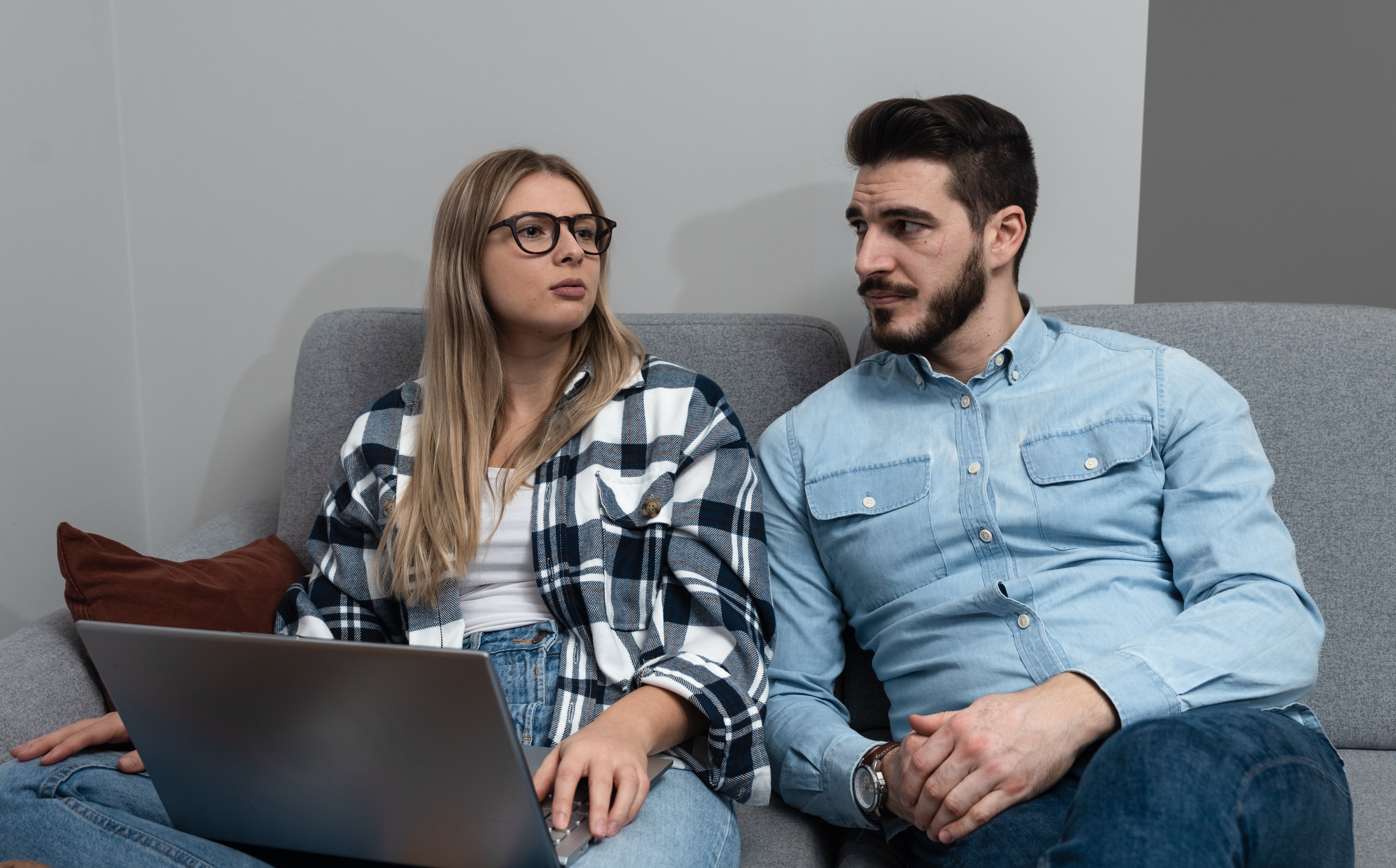 Una pareja sentada discutiendo algo mientras un ordenador portátil está en el regazo de la mujer | Foto: Shutterstock