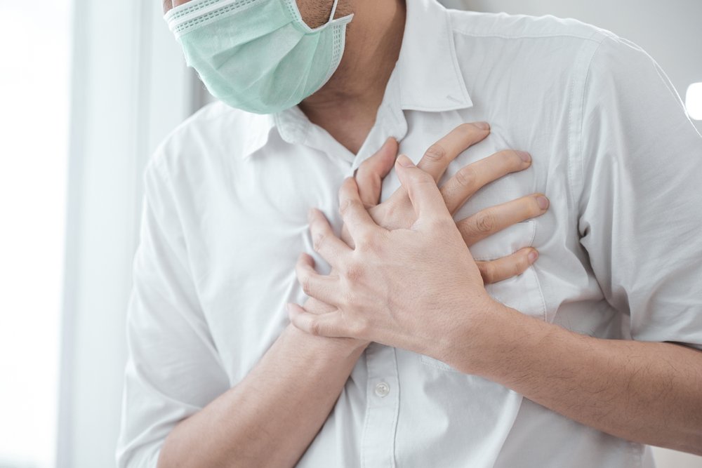 Un hombre con mascarilla médica agarrado su pecho debido al dolor. | Foto: Shutterstock