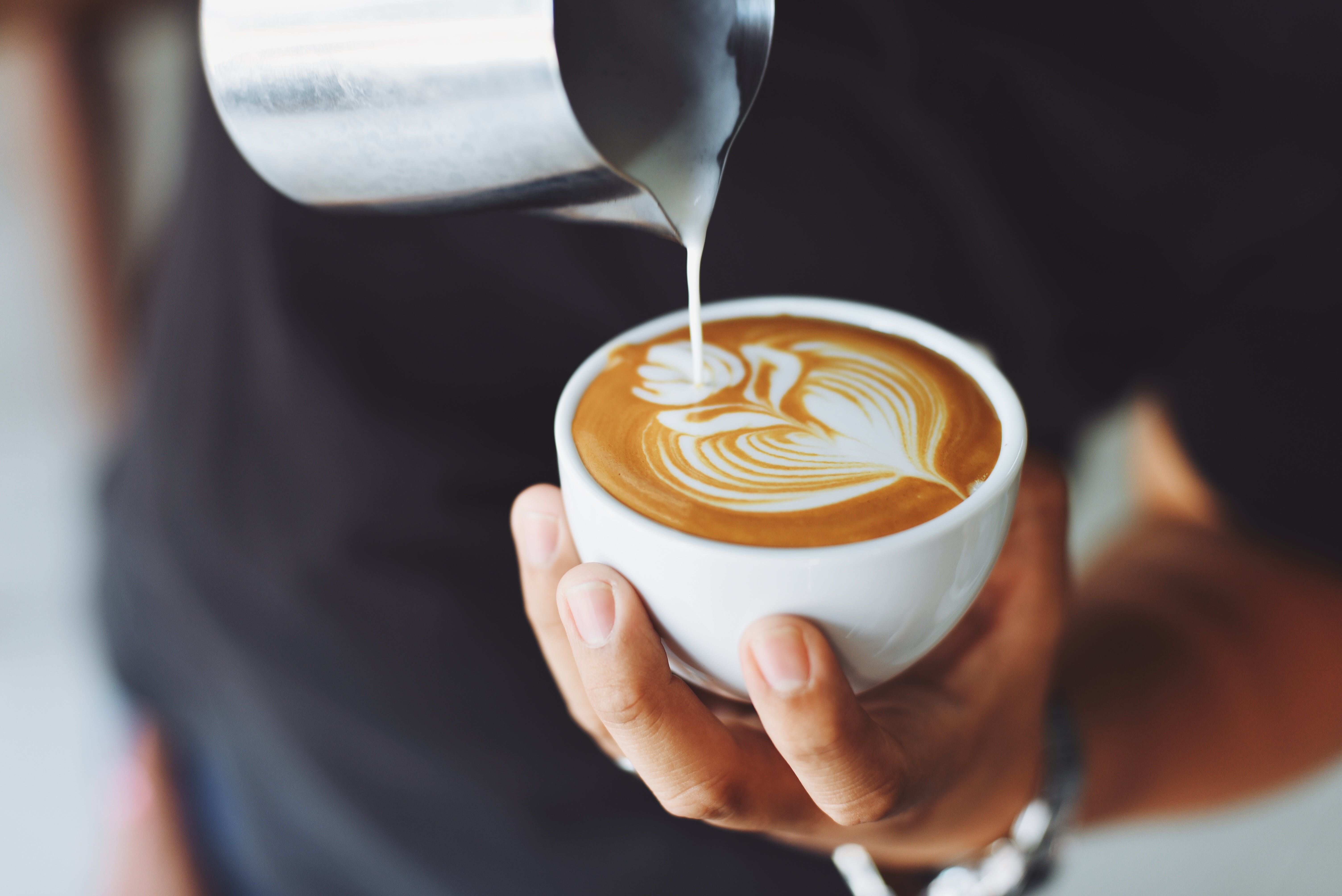 Una persona con una taza de café con leche en la mano. | Fuente: Pexels