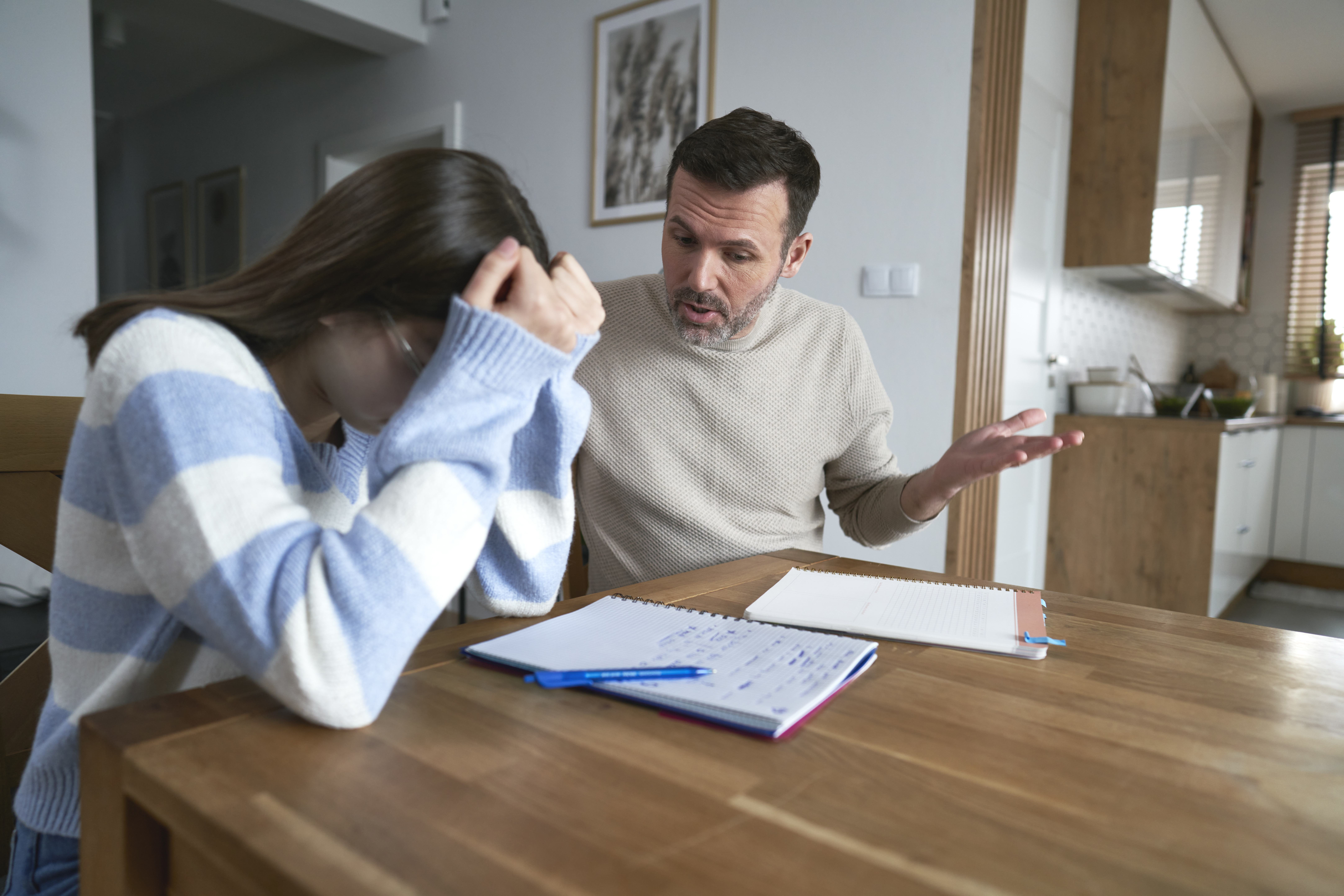 Padre enfadado con su hija adolescente haciendo los deberes en casa | Foto: Getty Images