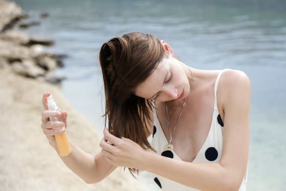 Mujer aplicando producto en su cabello bajo el sol. | Foto: Shutterstock