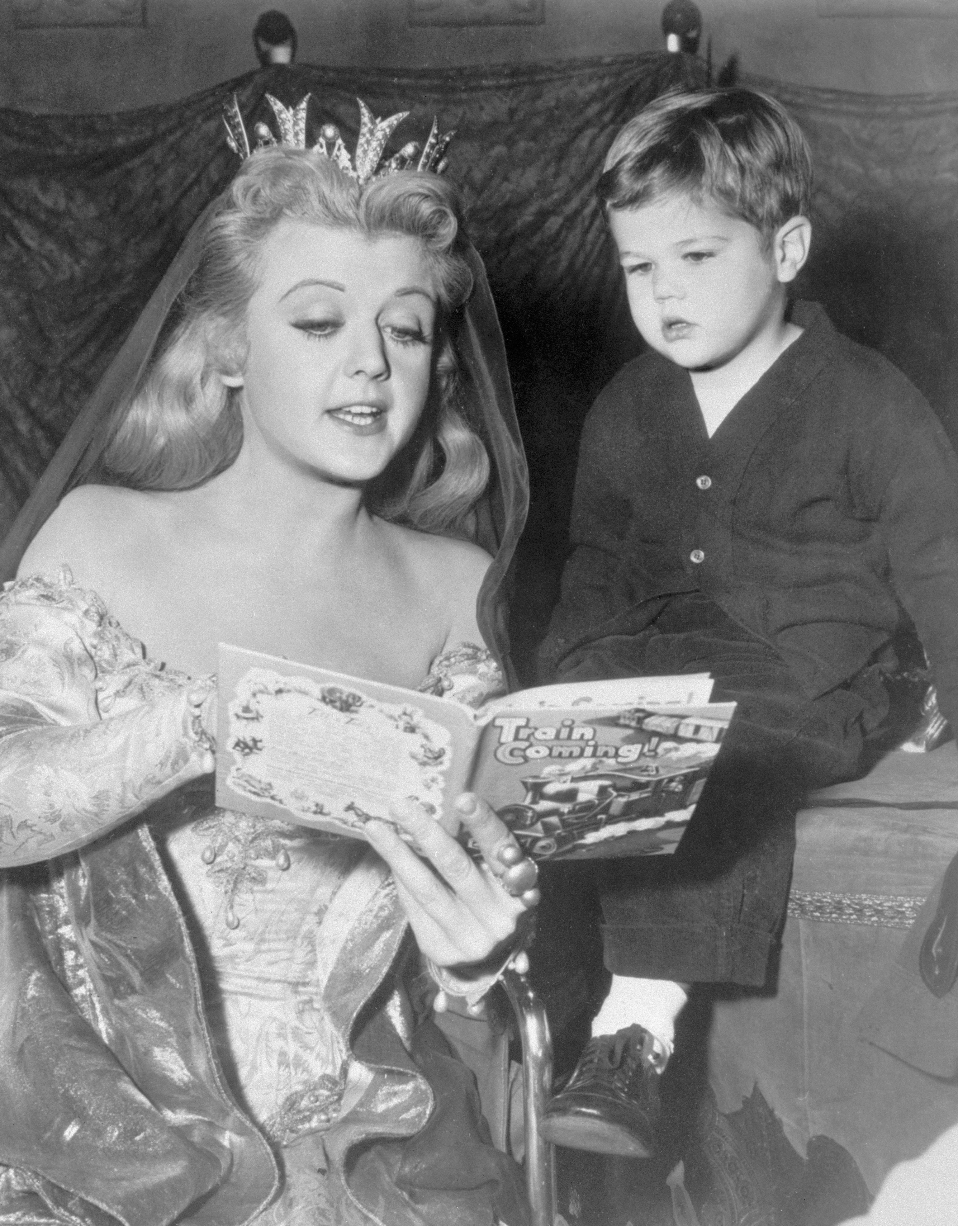 Angela Lansbury divierte a un pequeño visitante, su hijo Michael, al leerle un cuento de hadas moderno durante un descanso en una filmación en Hollywood, 1955. | Foto: Getty Images
