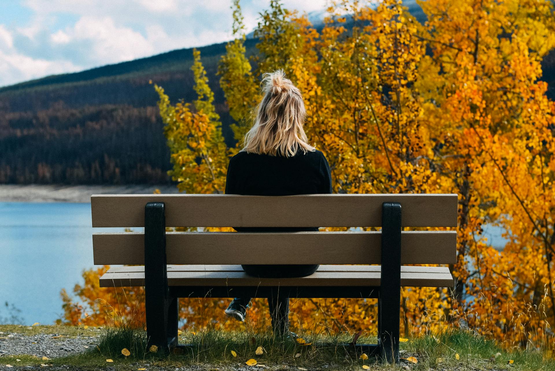 Una mujer sentada en un banco y mirando al lago | Fuente: Pexels