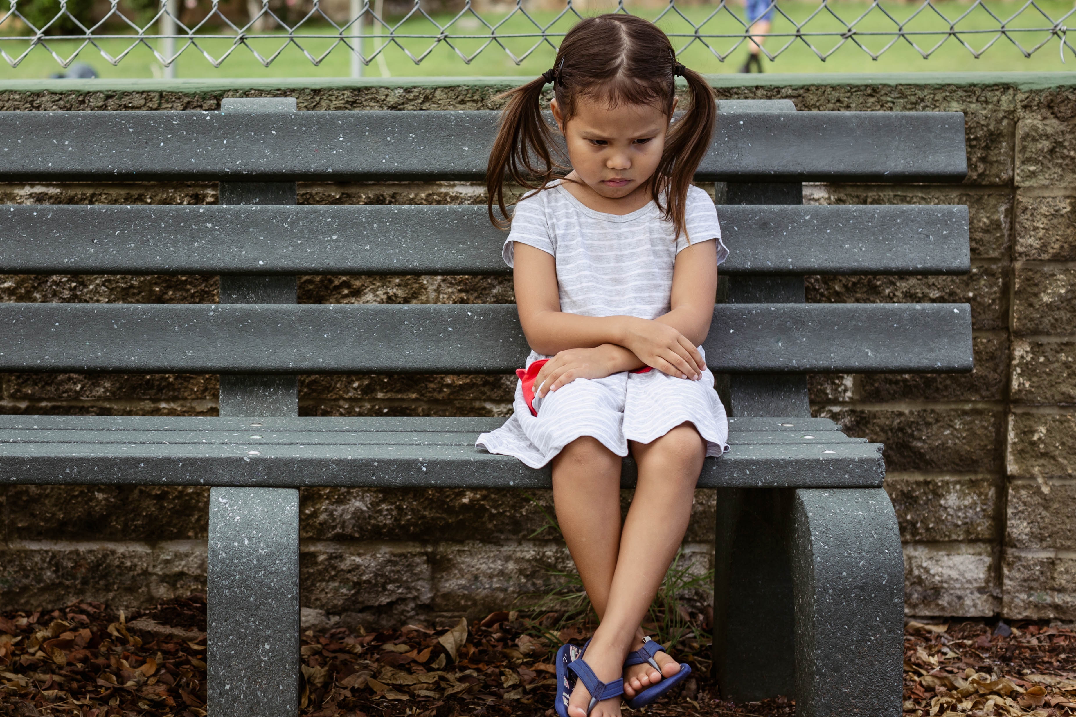 Una niña infeliz sentada sola en un banco. | Foto: Shutterstock
