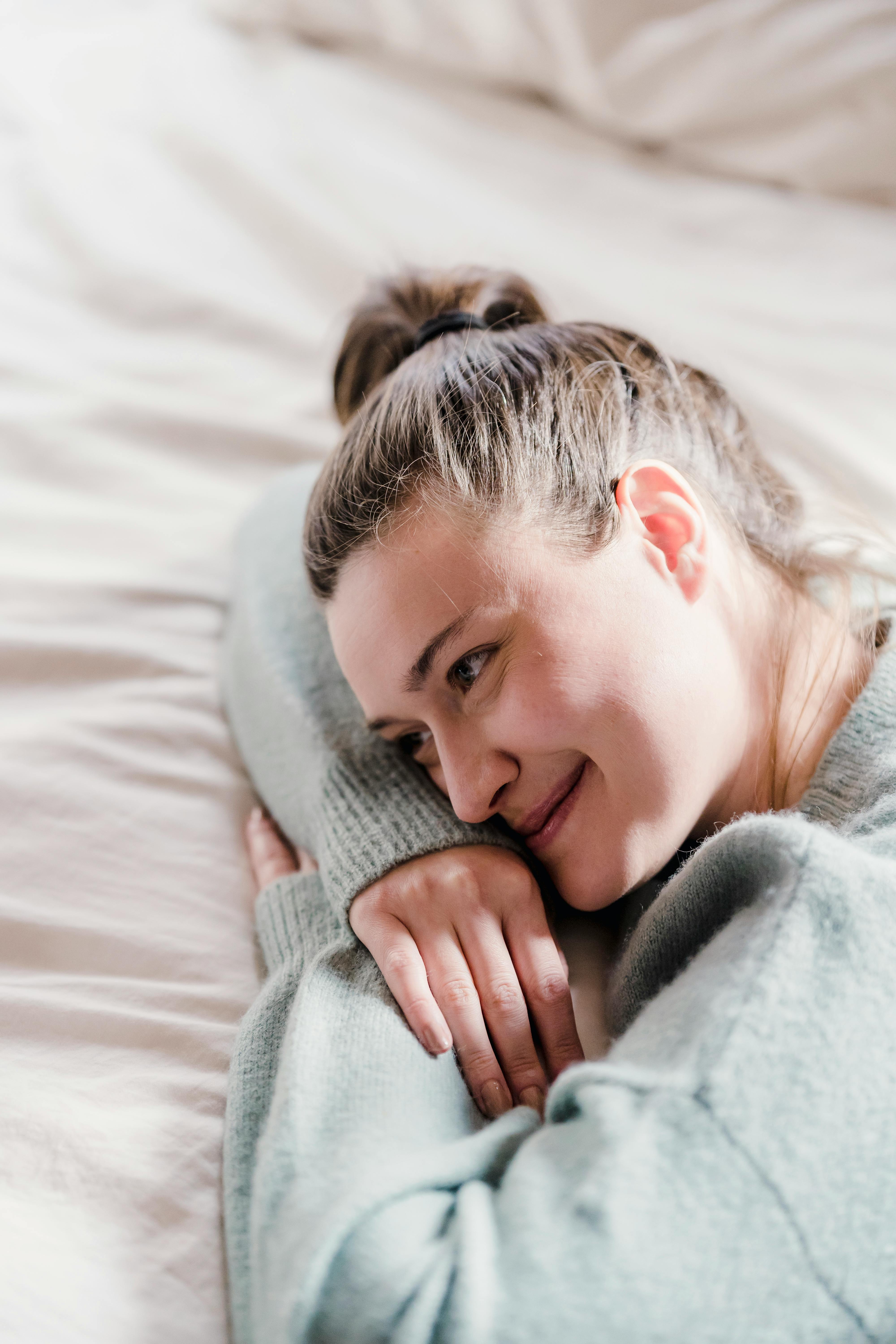 Una mujer feliz tumbada en una cama mientras piensa | Fuente: Pexels