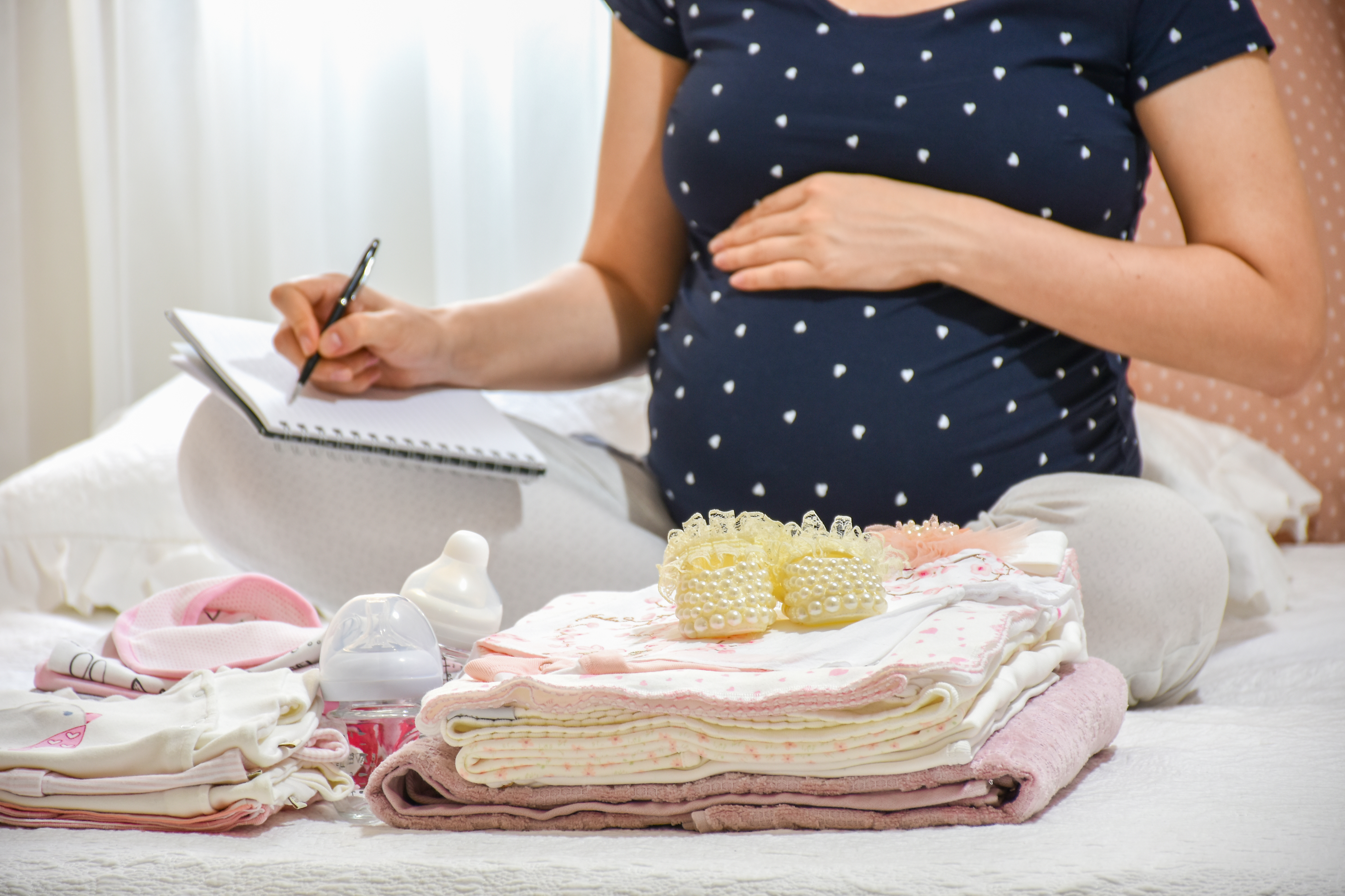 Una mujer embarazada con ropa de bebé | Fuente: Shutterstock