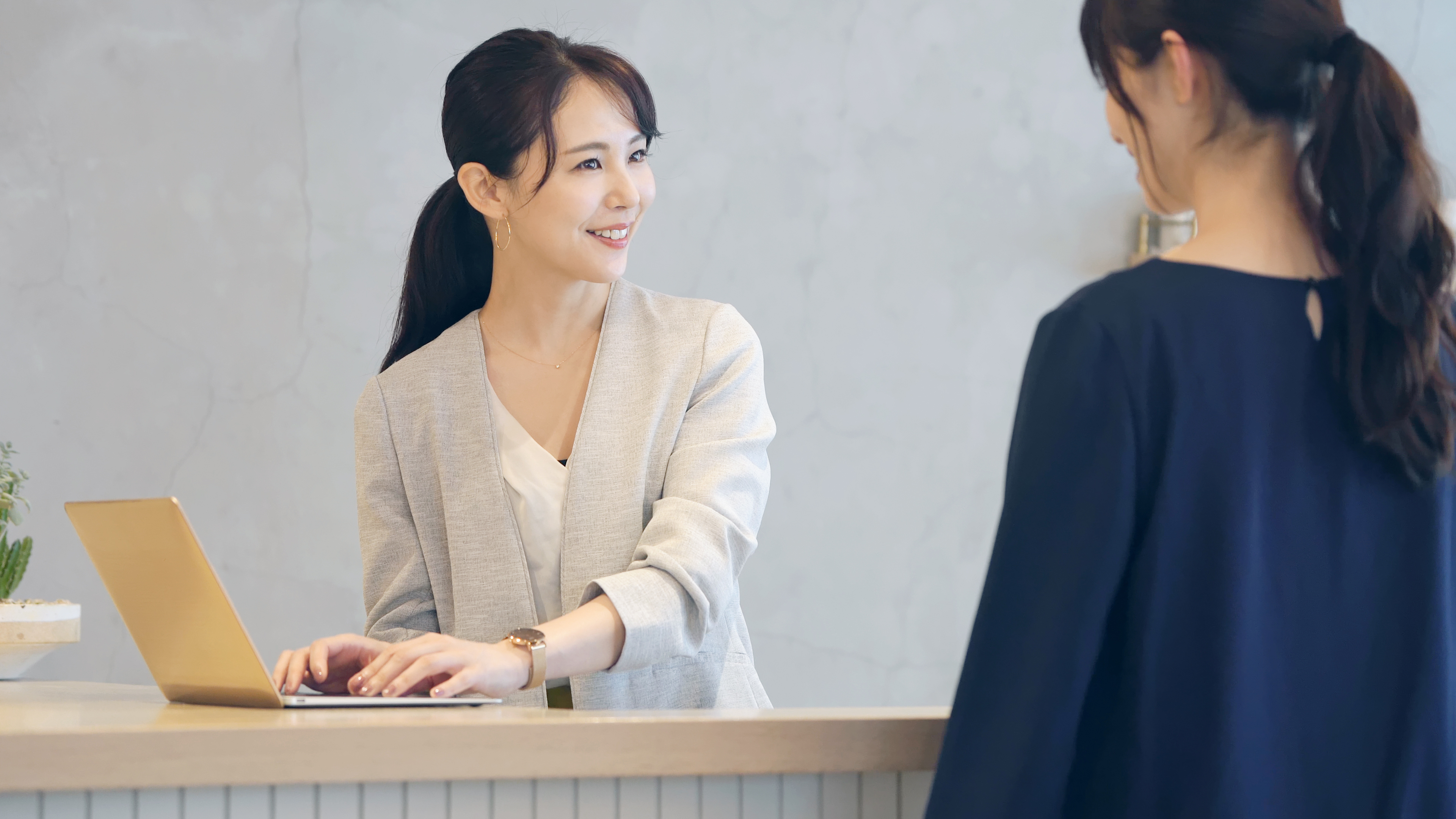 Una mujer hablando con una recepcionista asiática | Fuente: Shutterstock