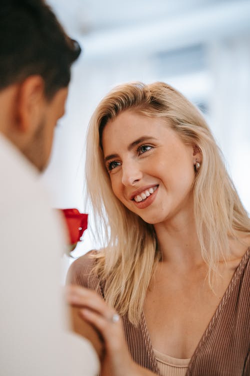 Joven sonrie al recibir una rosa de manos de un hombre. | Foto: Pexels