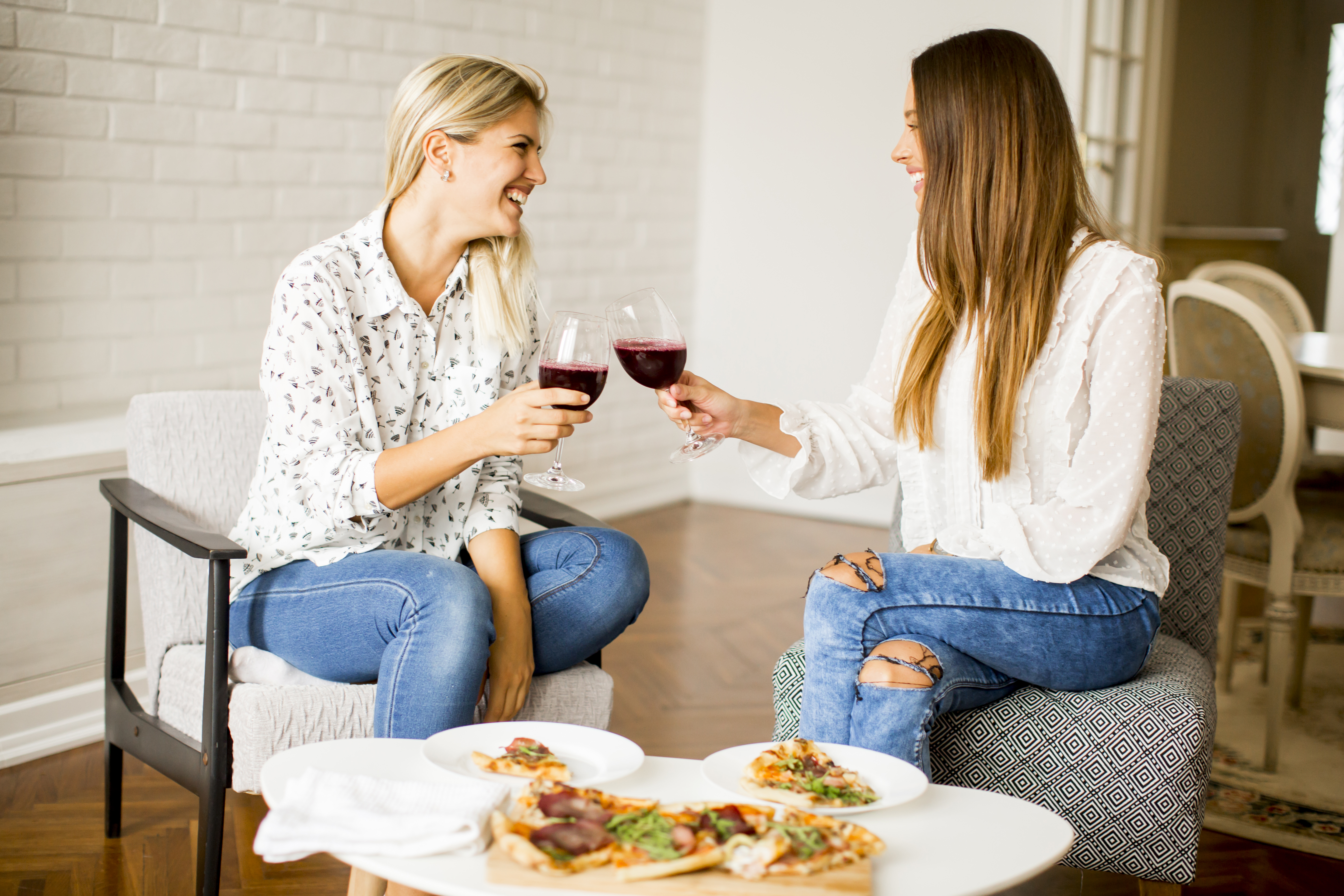 Jovencitas guapas comiendo pizza y bebiendo vino tinto | Foto: Getty Images