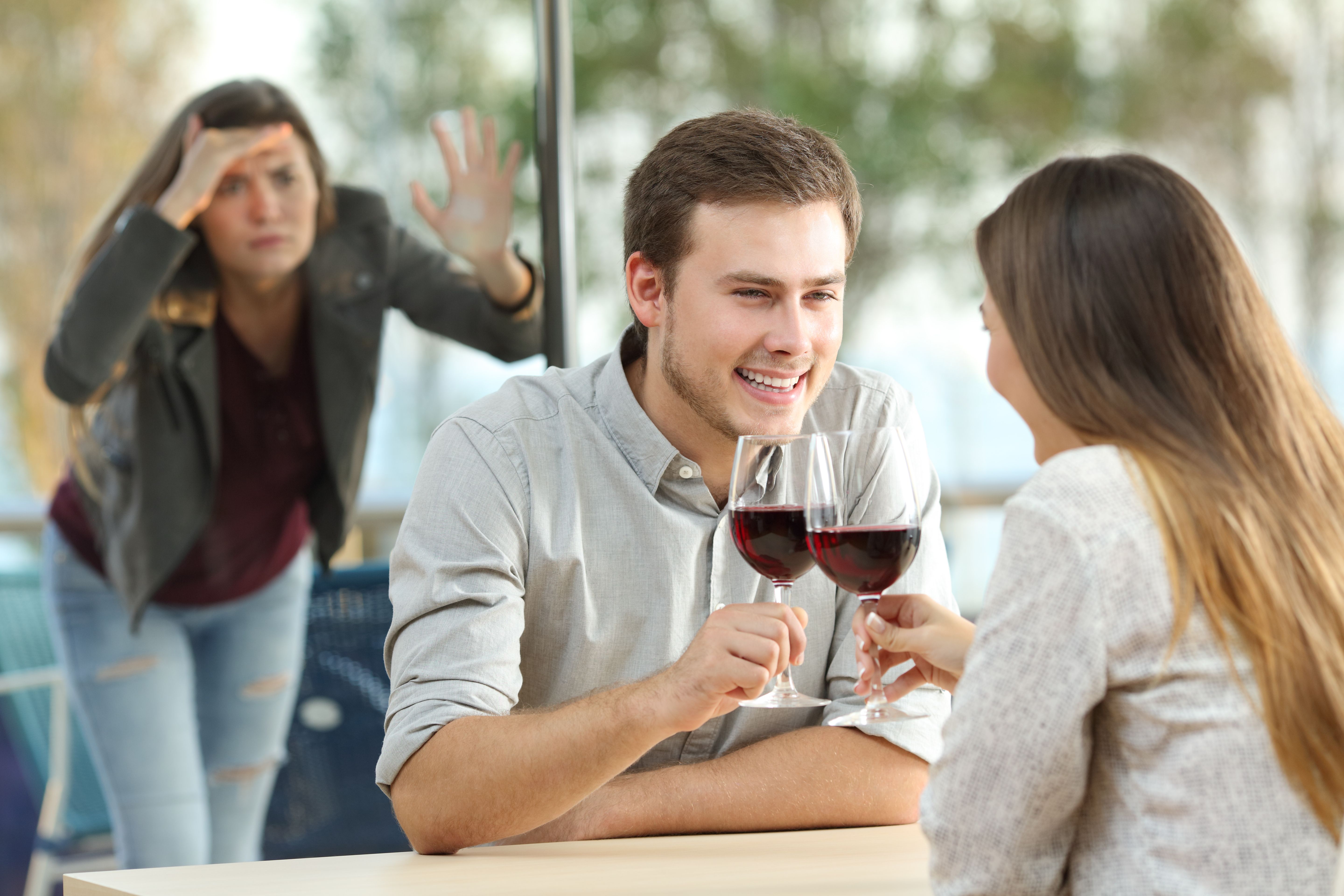 Una mujer espía a una pareja tomando vino | Foto: Shutterstock