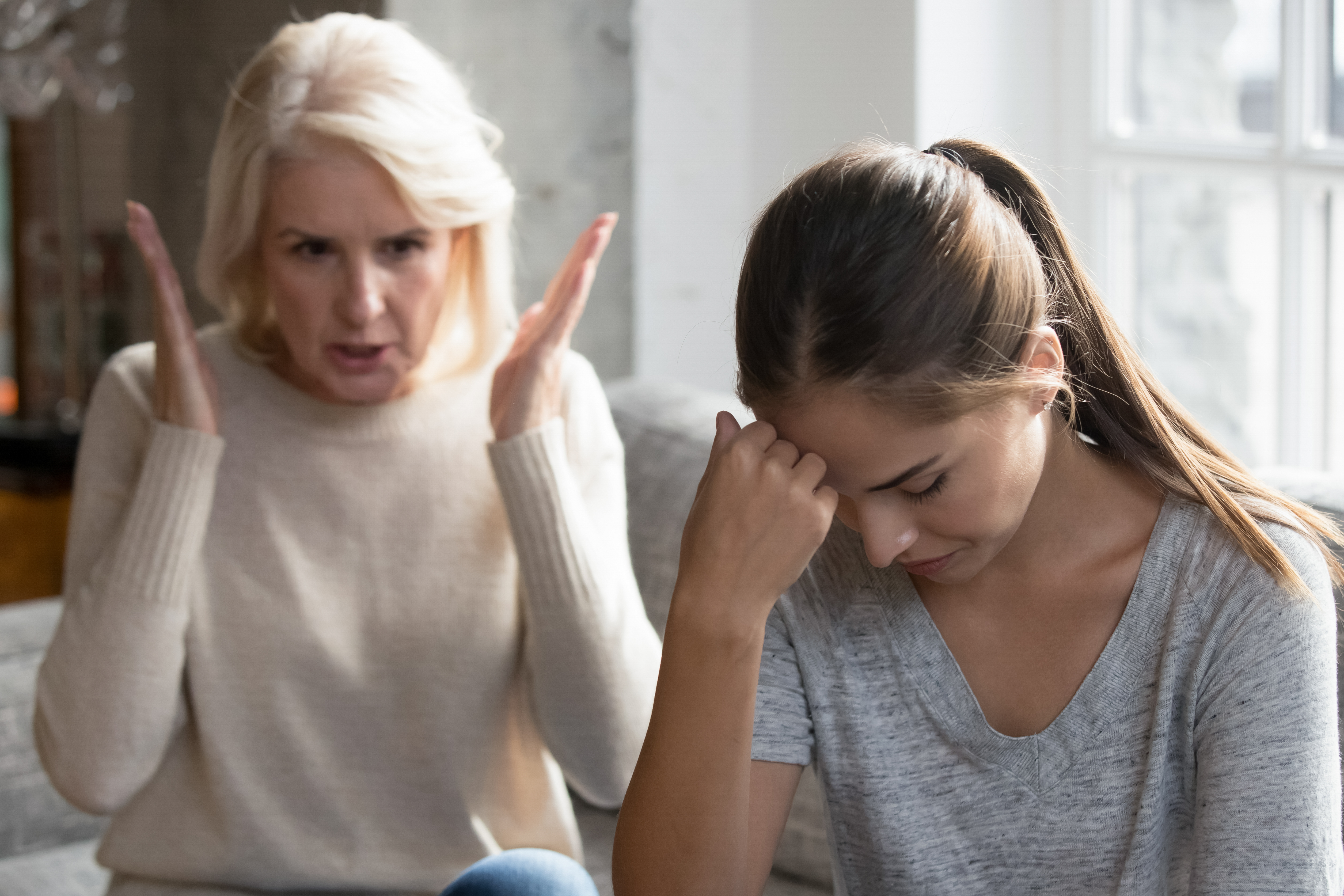 Una mujer joven disgustada discutiendo con otra mayor sentada en un sofá. | Foto: Shutterstock