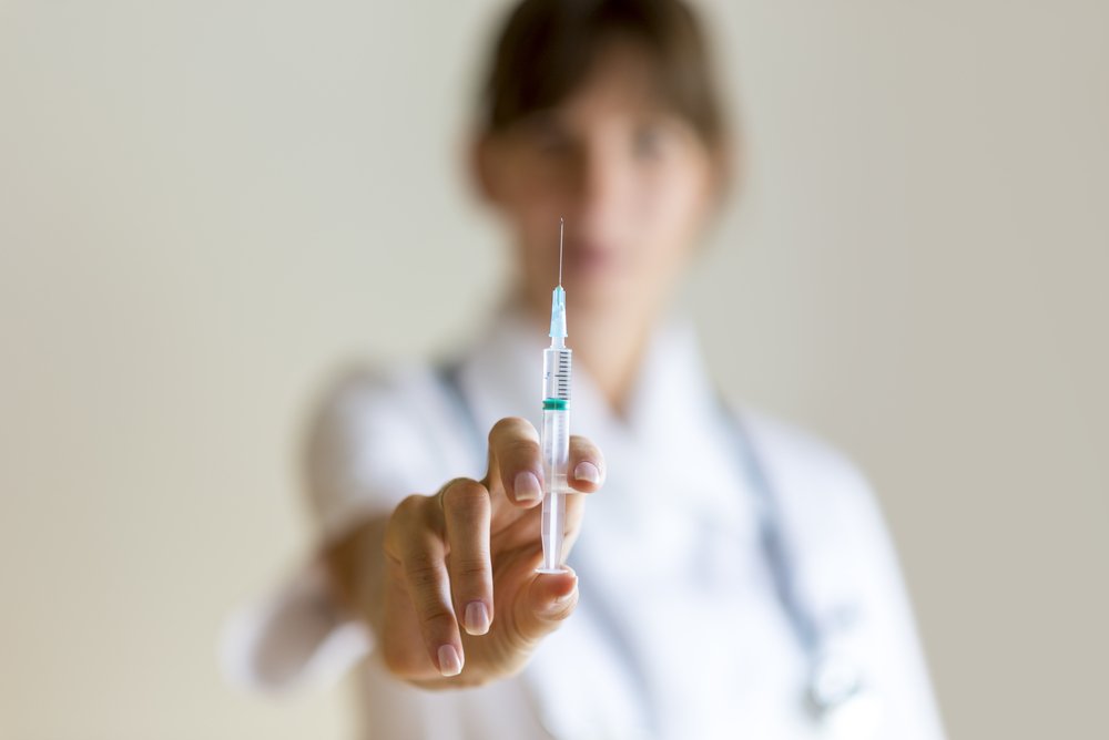 Enfermera sosteniendo una inyección en su mano. Fuente: Shutterstock