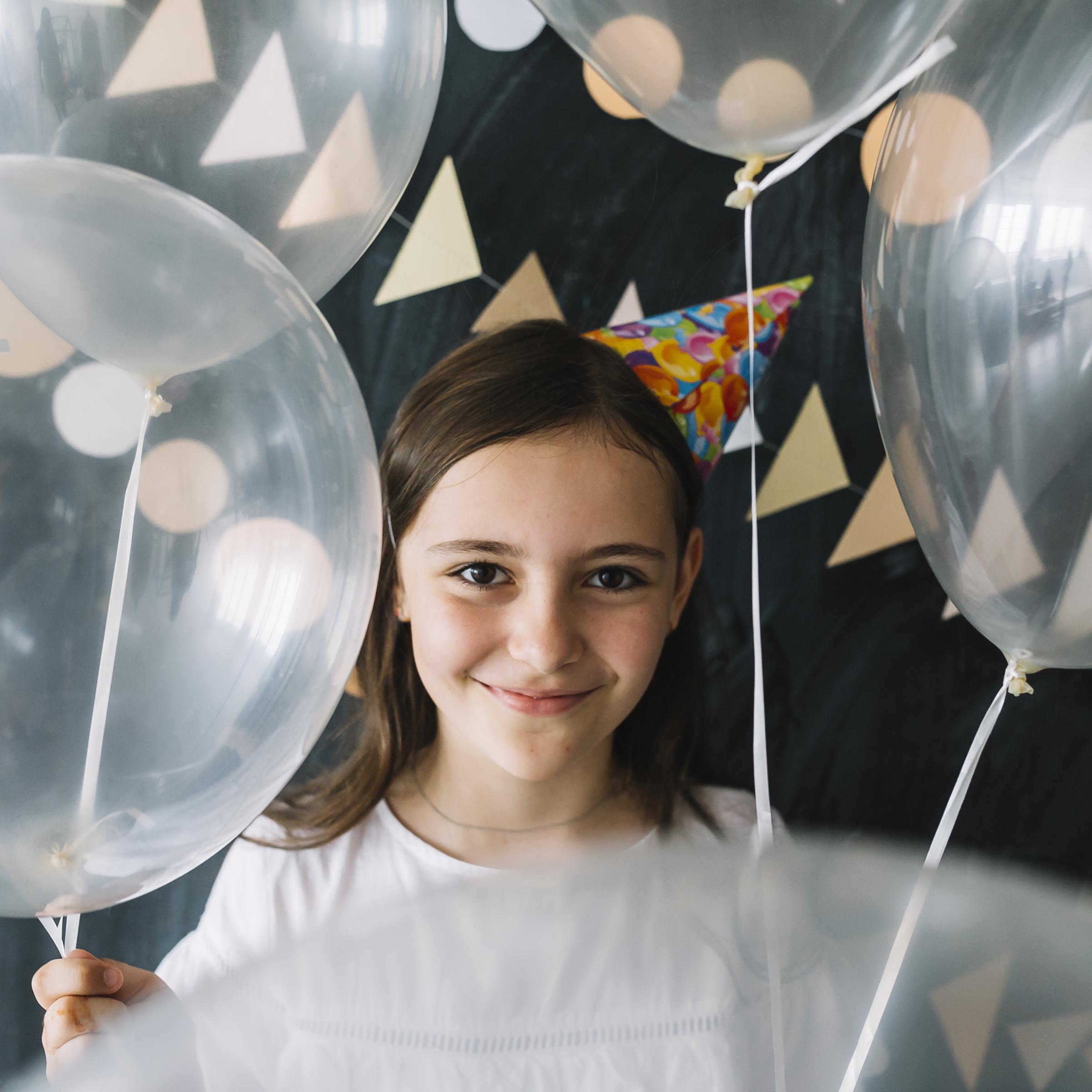 Niña sujetando globos en una fiesta | Fuente: Freepik