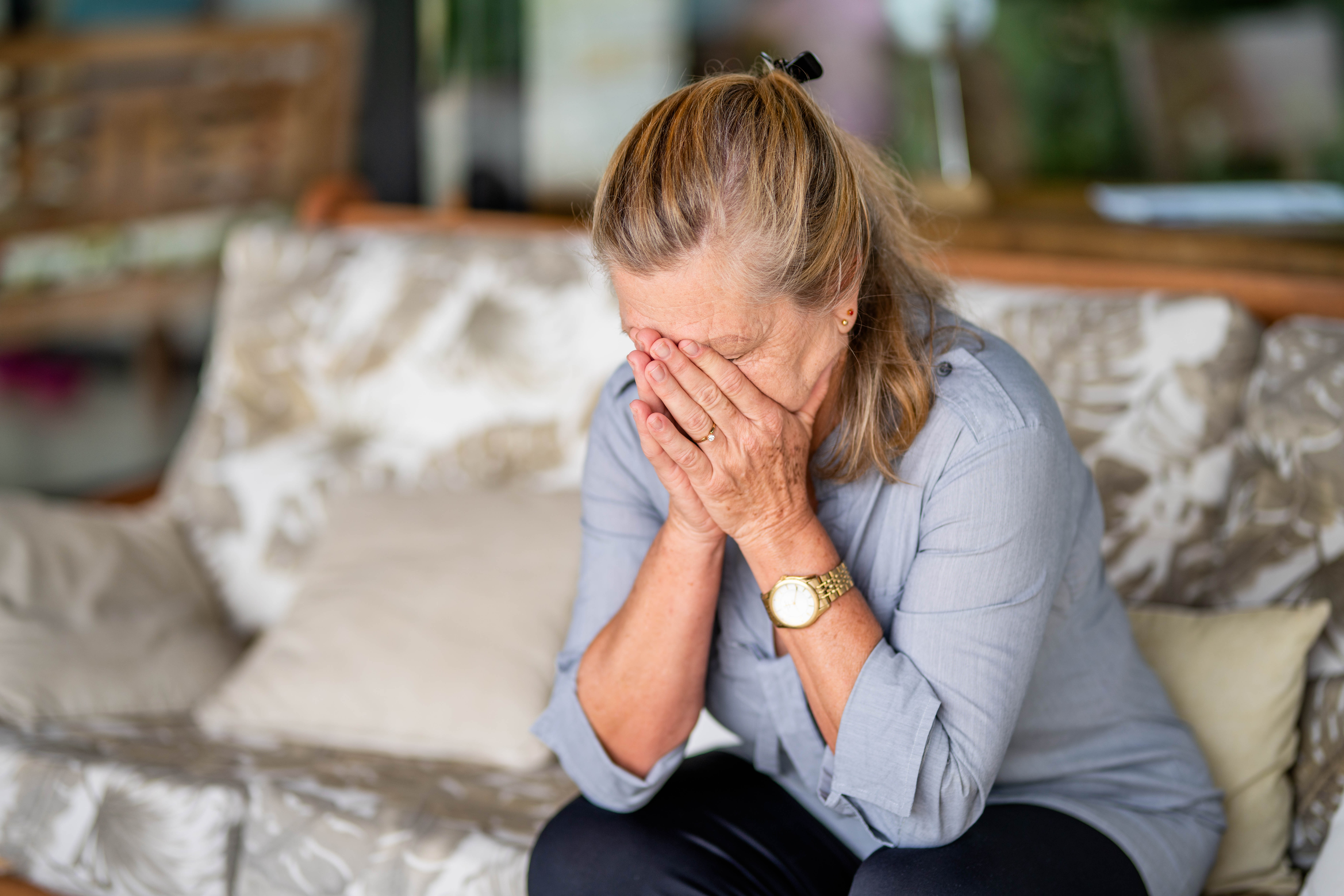 Mujer mayor con depresión sentada con la cabeza entre las manos en su casa | Foto: Getty Images