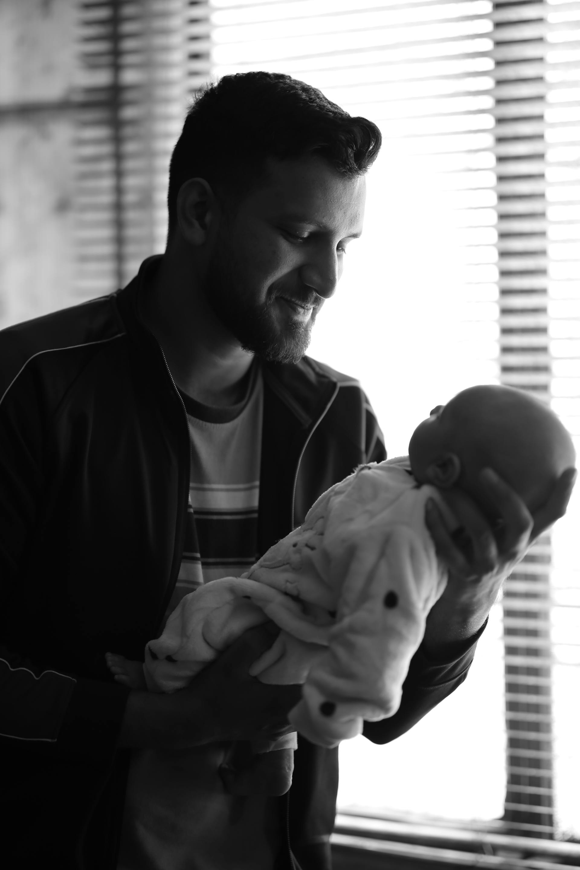 Foto in scala di grigi di un padre che tiene in braccio un neonato | Fonte: Pexels