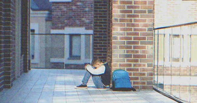 Un niño sentado con la cabeza entre las rodillas | Foto: Shutterstock