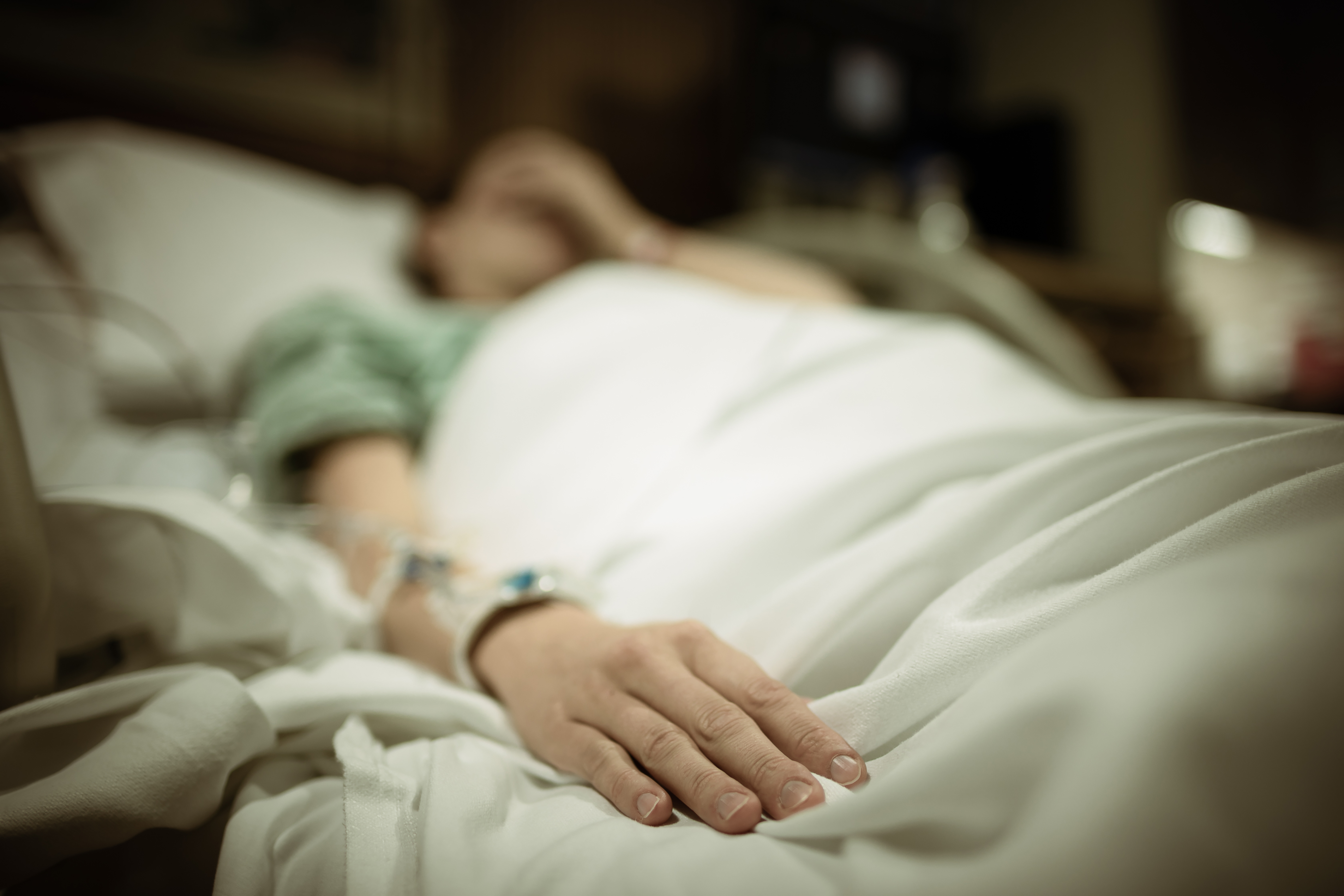 Mujer triste en la cama de un hospital | Fuente: Shutterstock